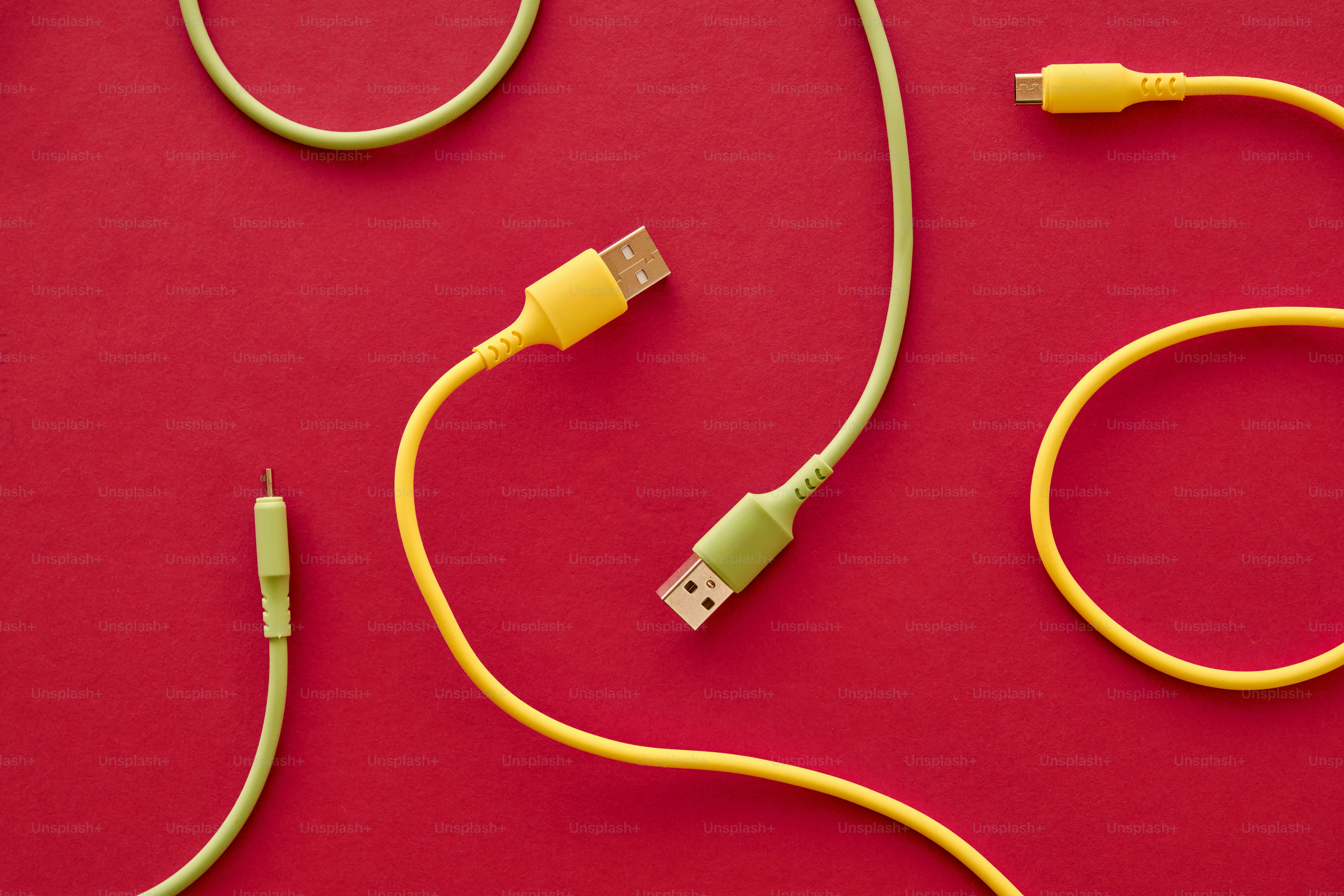 Yellow and green charging cables on red background