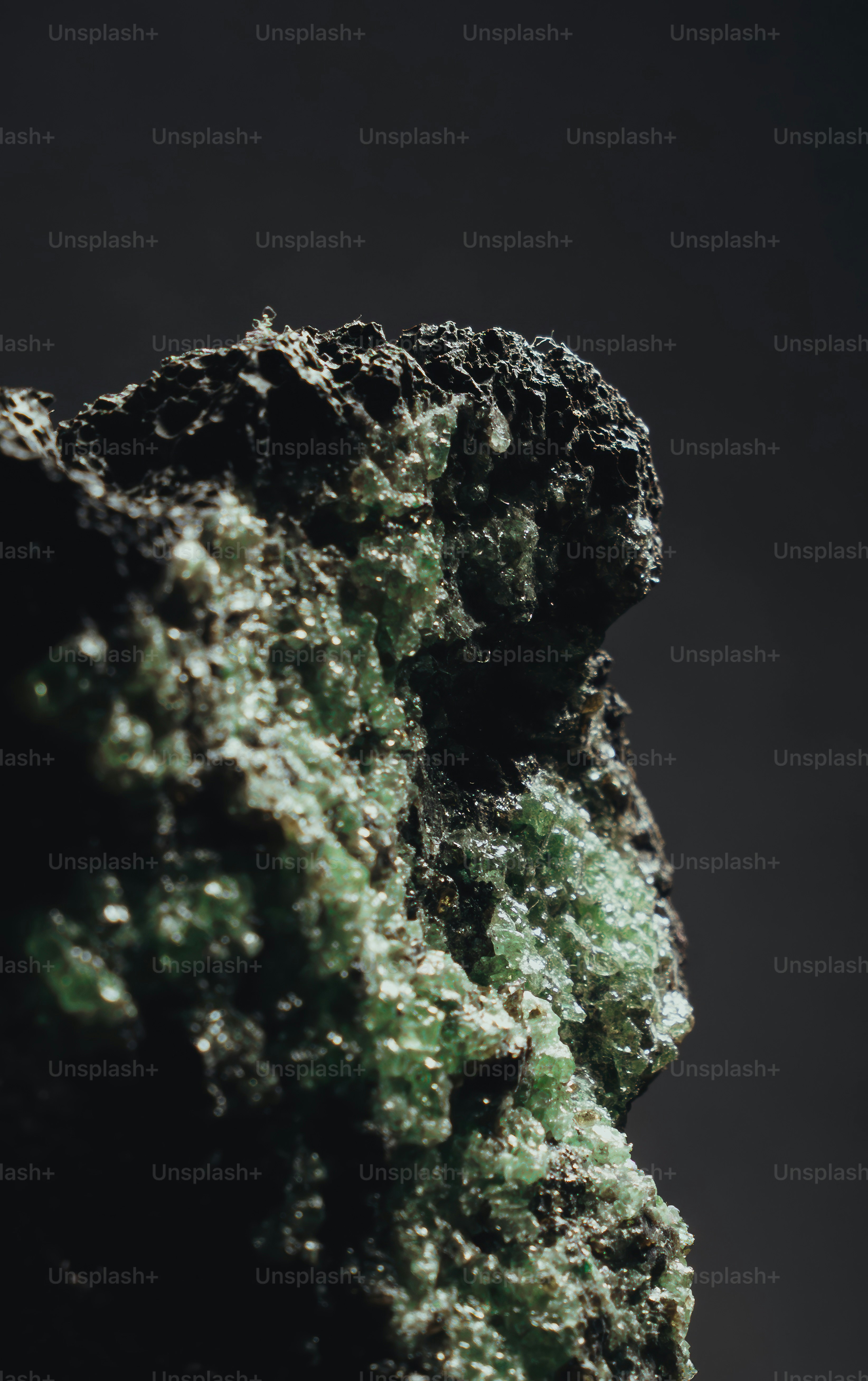 Close-up of a dark rock with green crystalline formations.