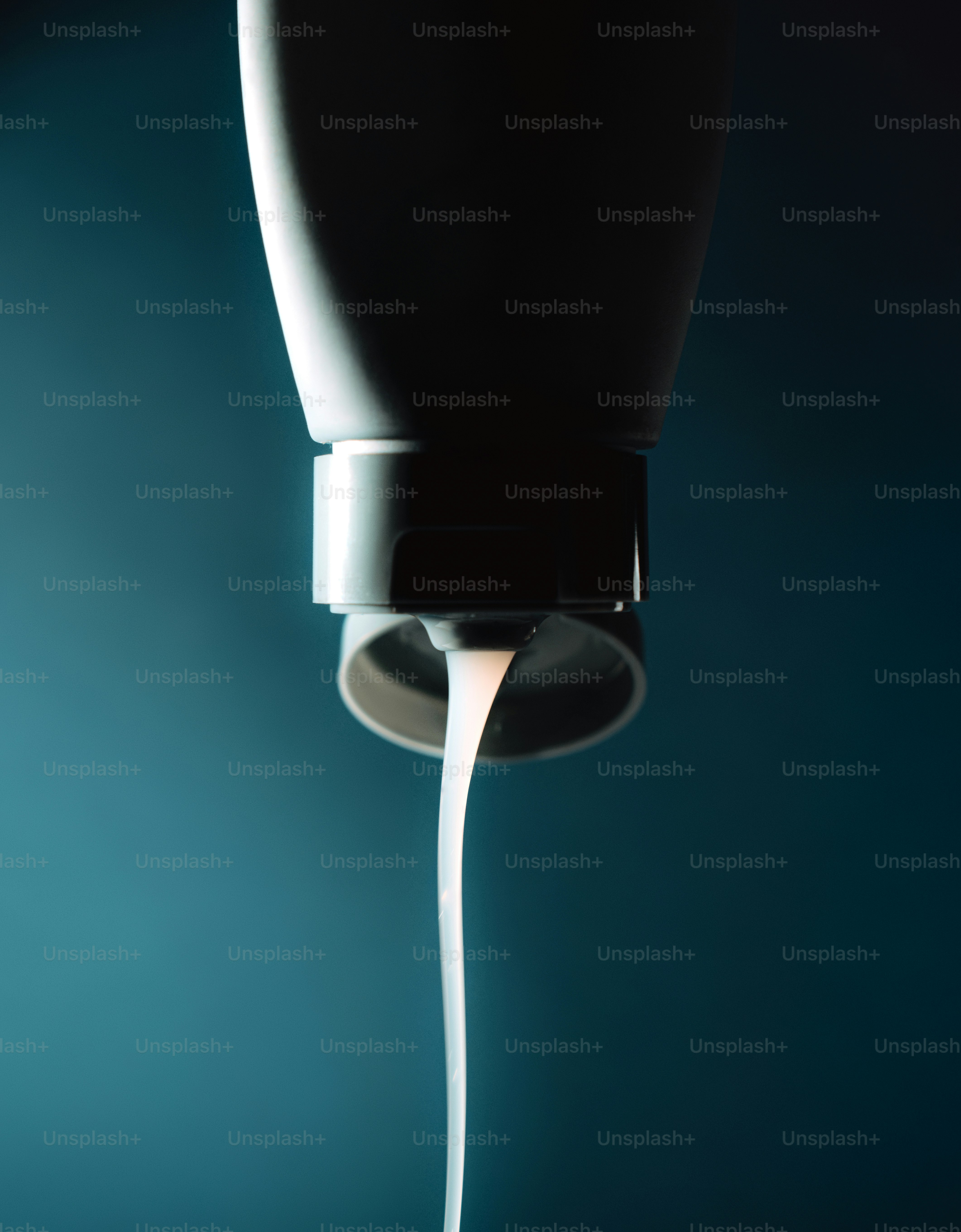 White liquid pouring from a tube against blue.