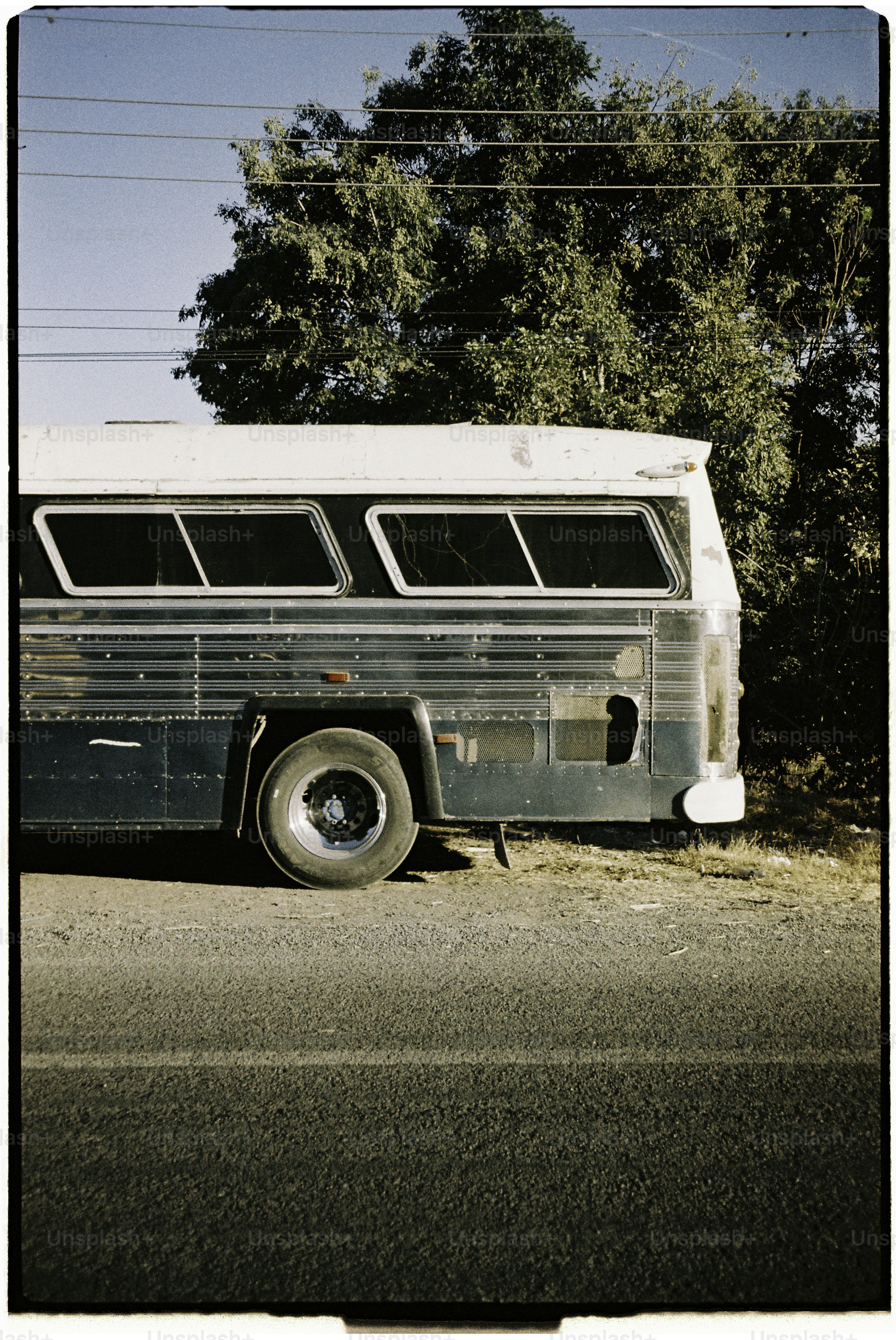 An old blue bus parked by a road.