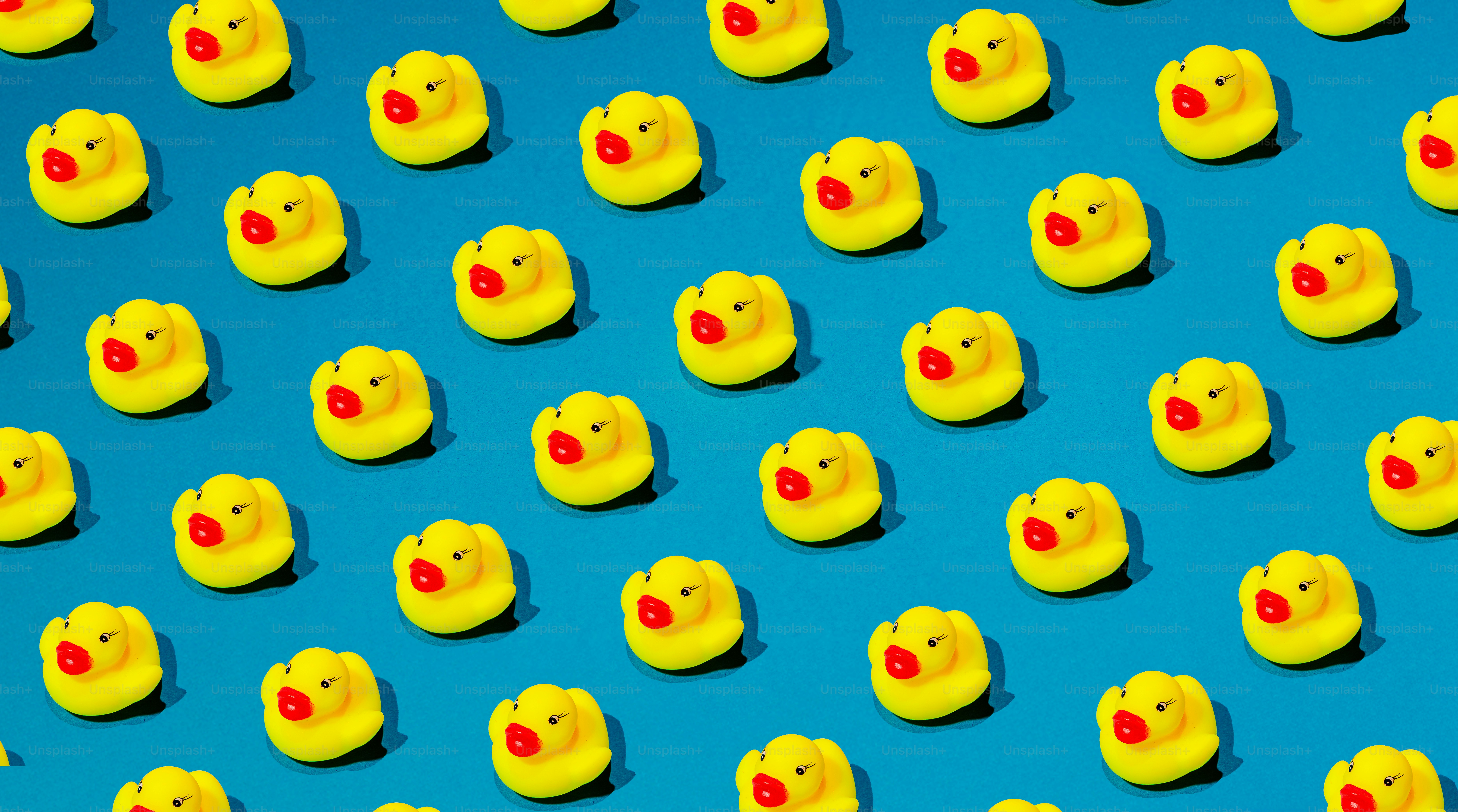 Many yellow rubber ducks arranged on a blue background