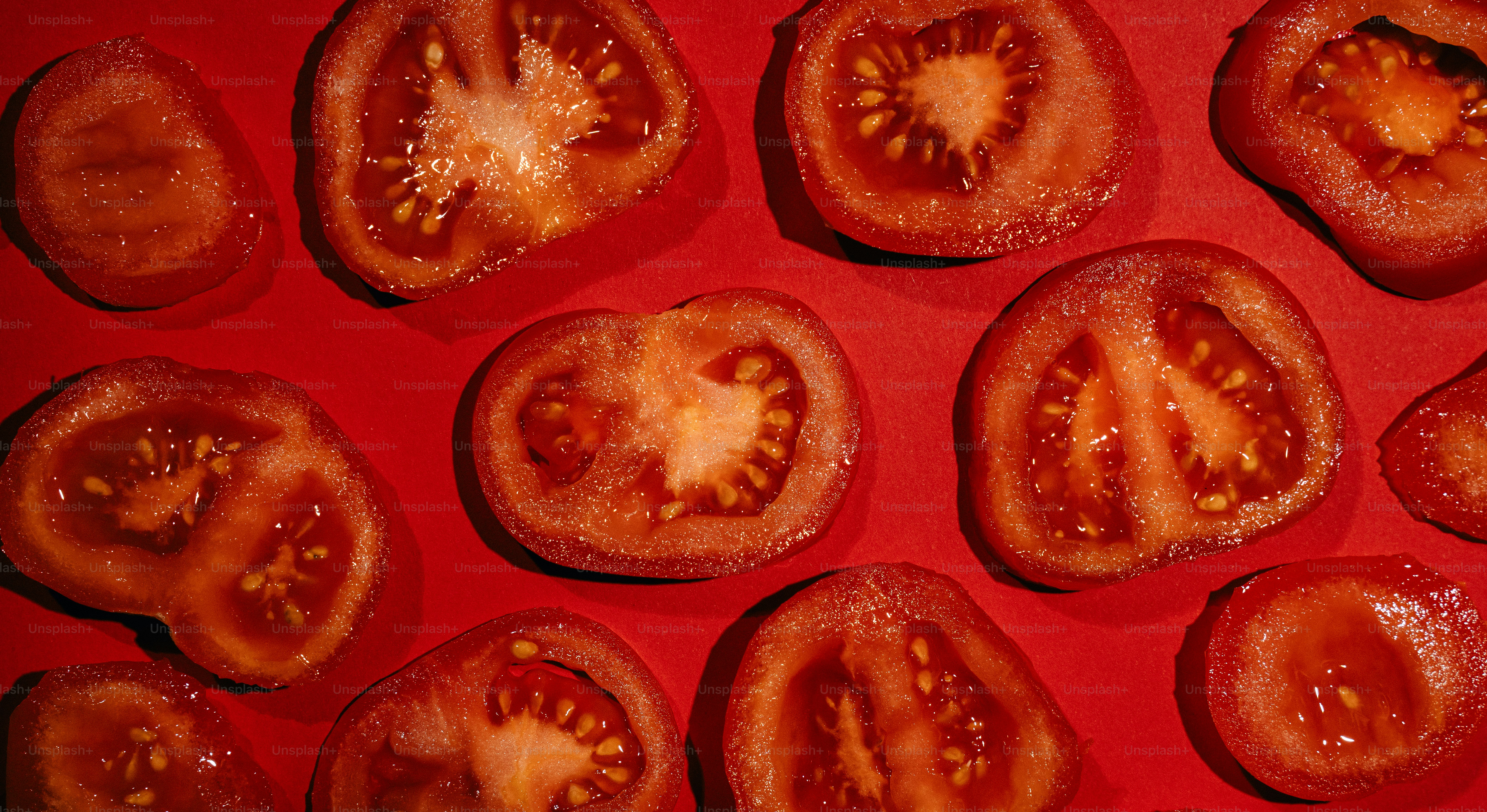 Several sliced tomatoes arranged on a red surface.