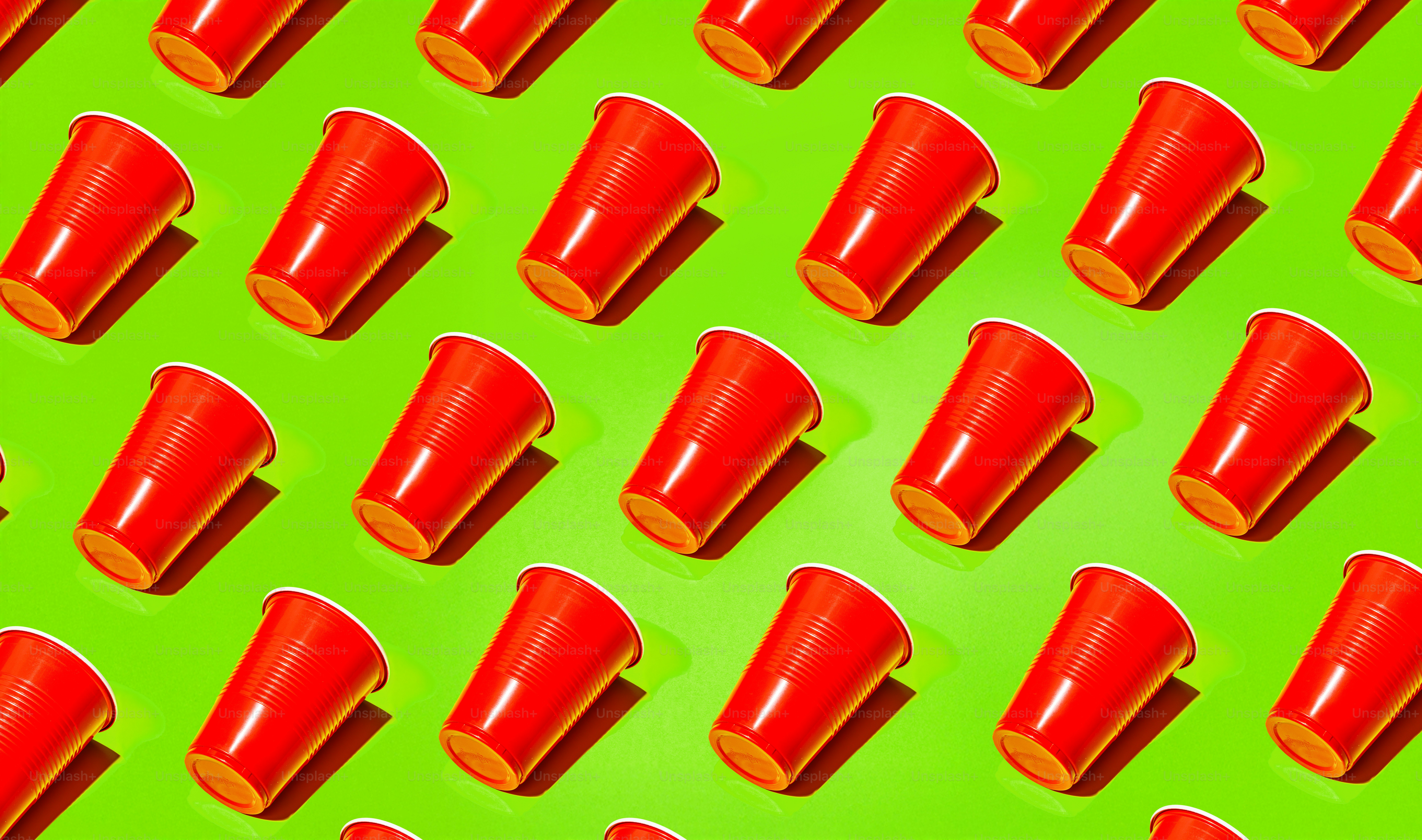 Padrão de copos de plástico vermelho em um fundo verde