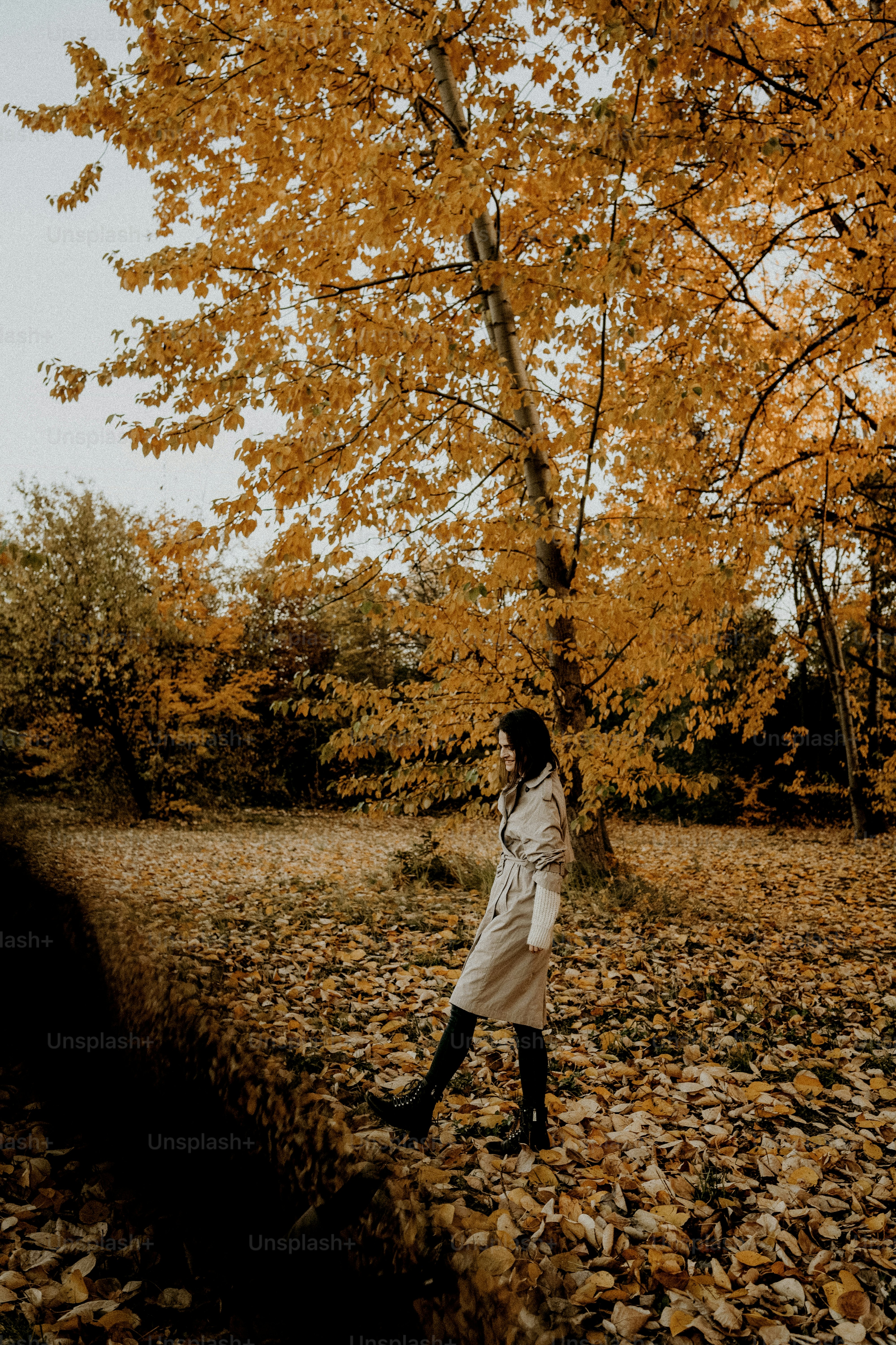 Woman walking through fallen autumn leaves in a park