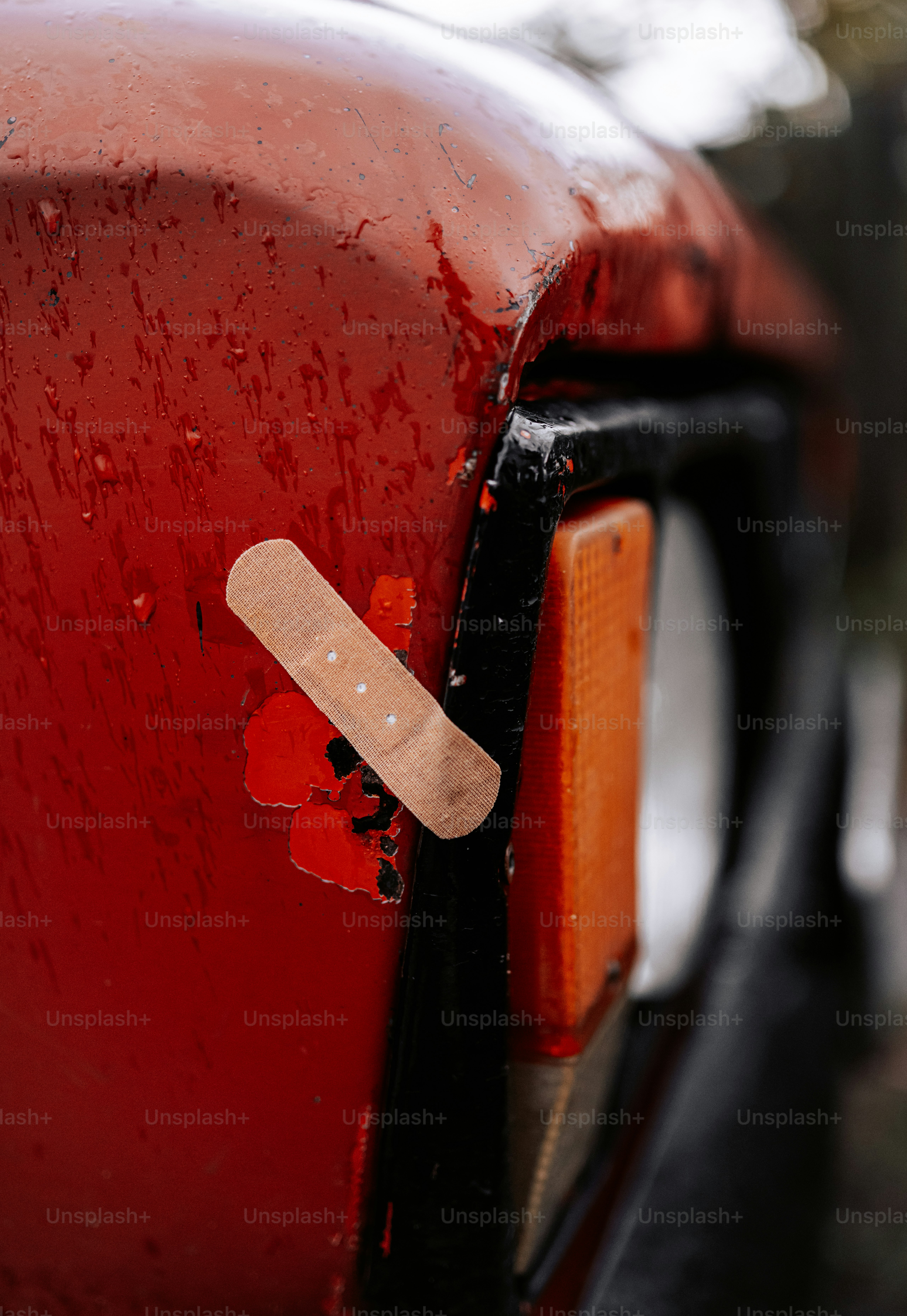 A bandage is placed on a damaged red car.