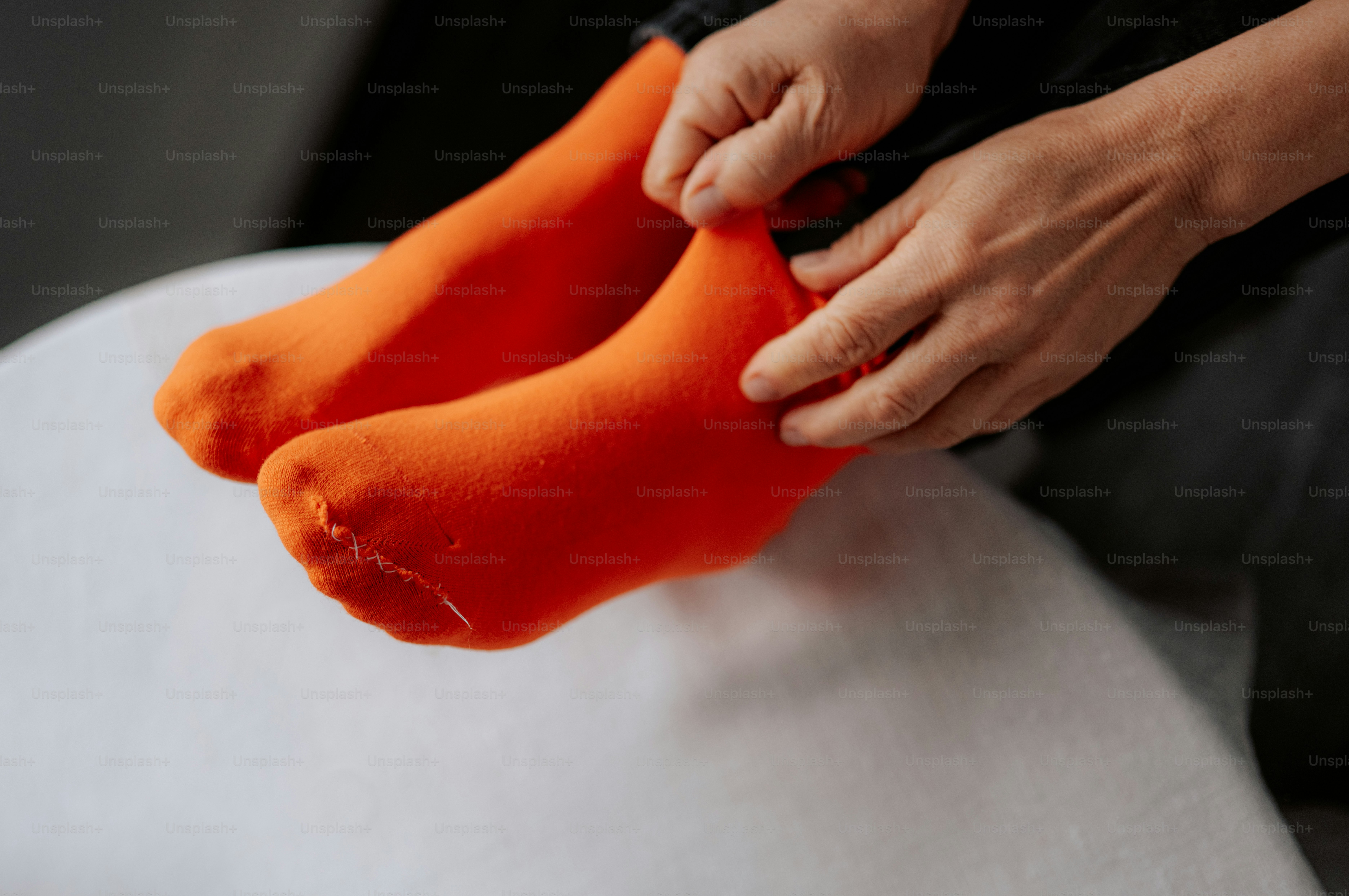 Hands pulling on bright orange socks