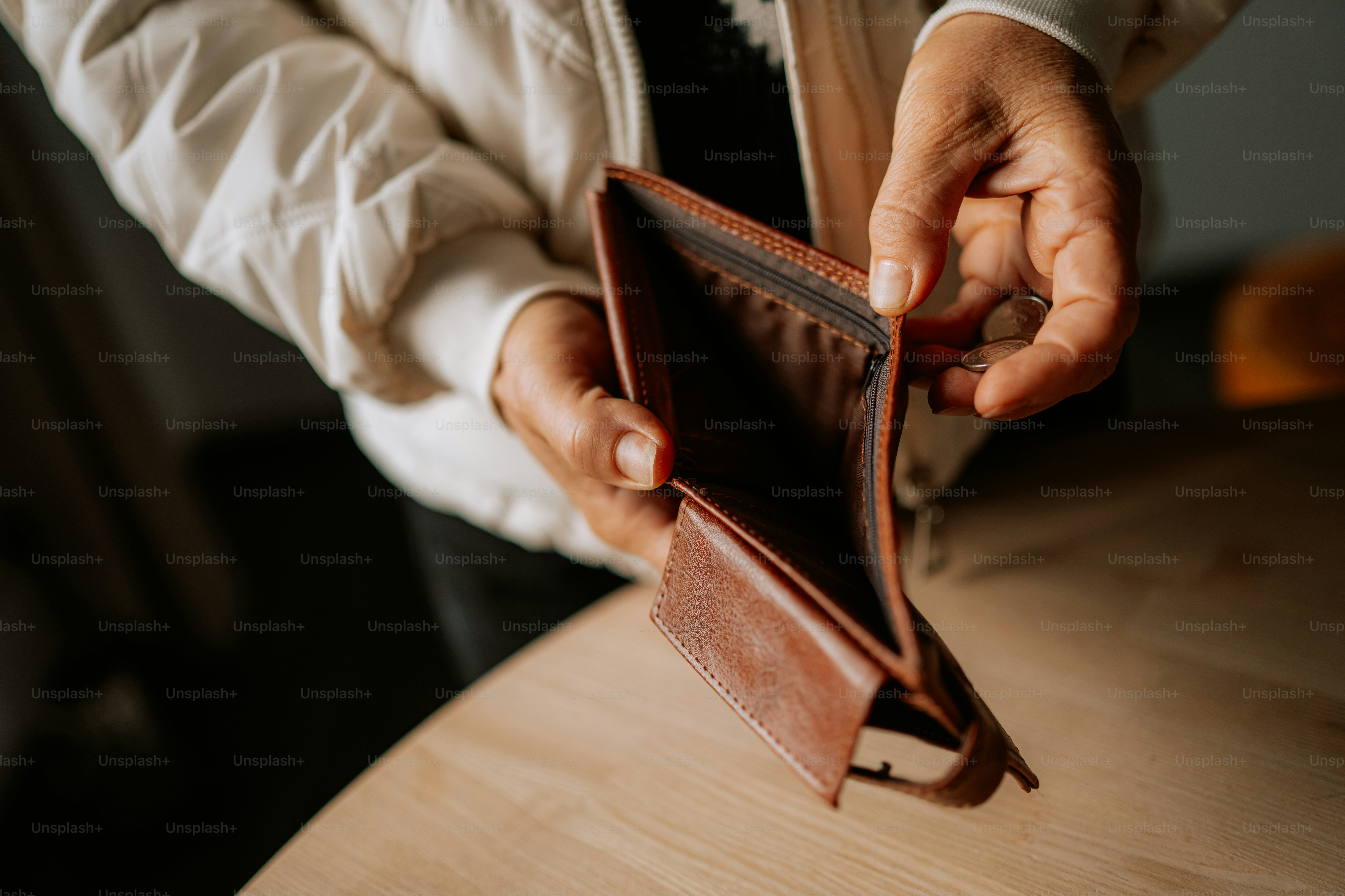 Hände, die ein leeres braunes Lederportemonnaie halten