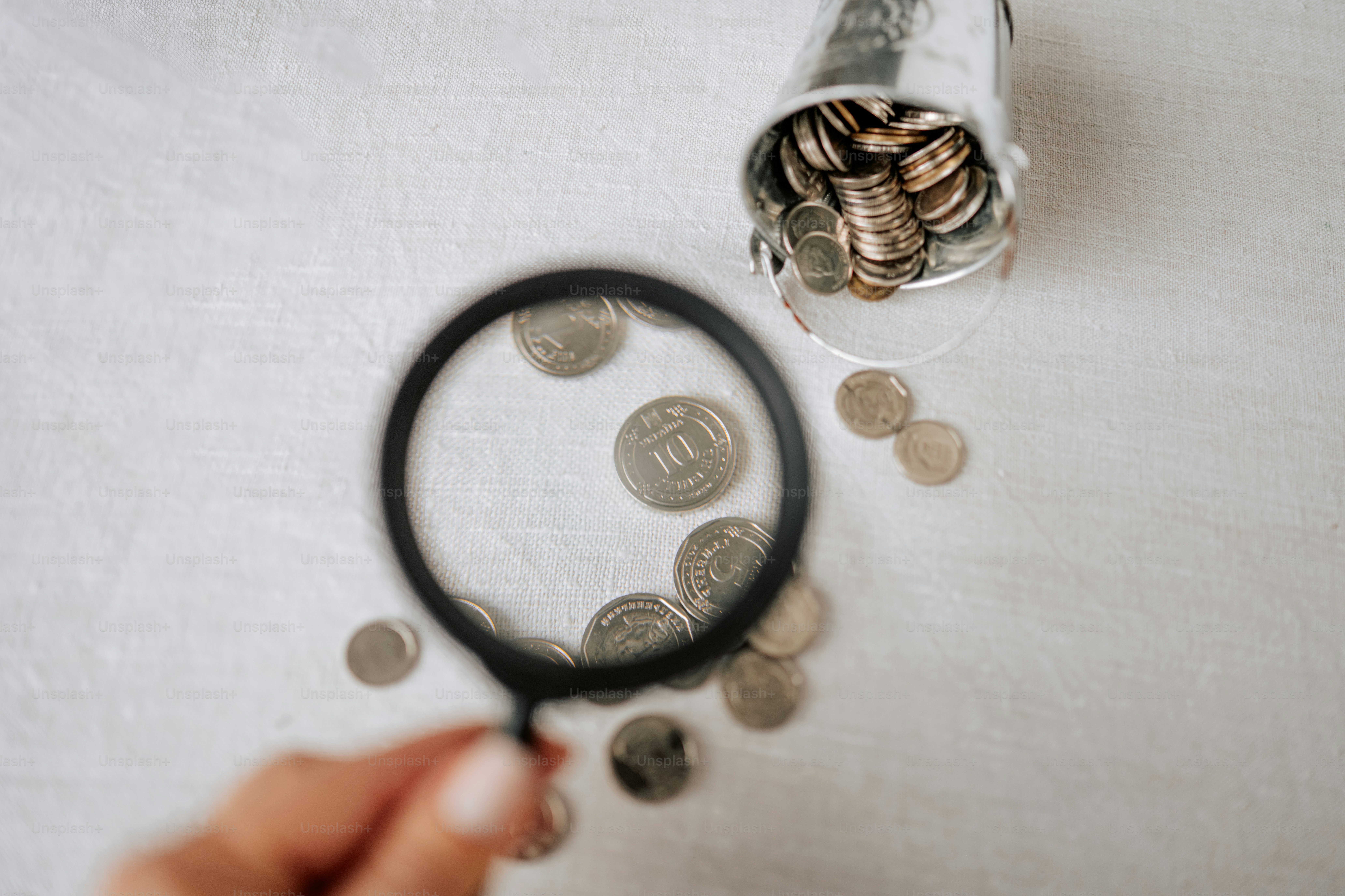Magnifying glass over scattered coins and bucket