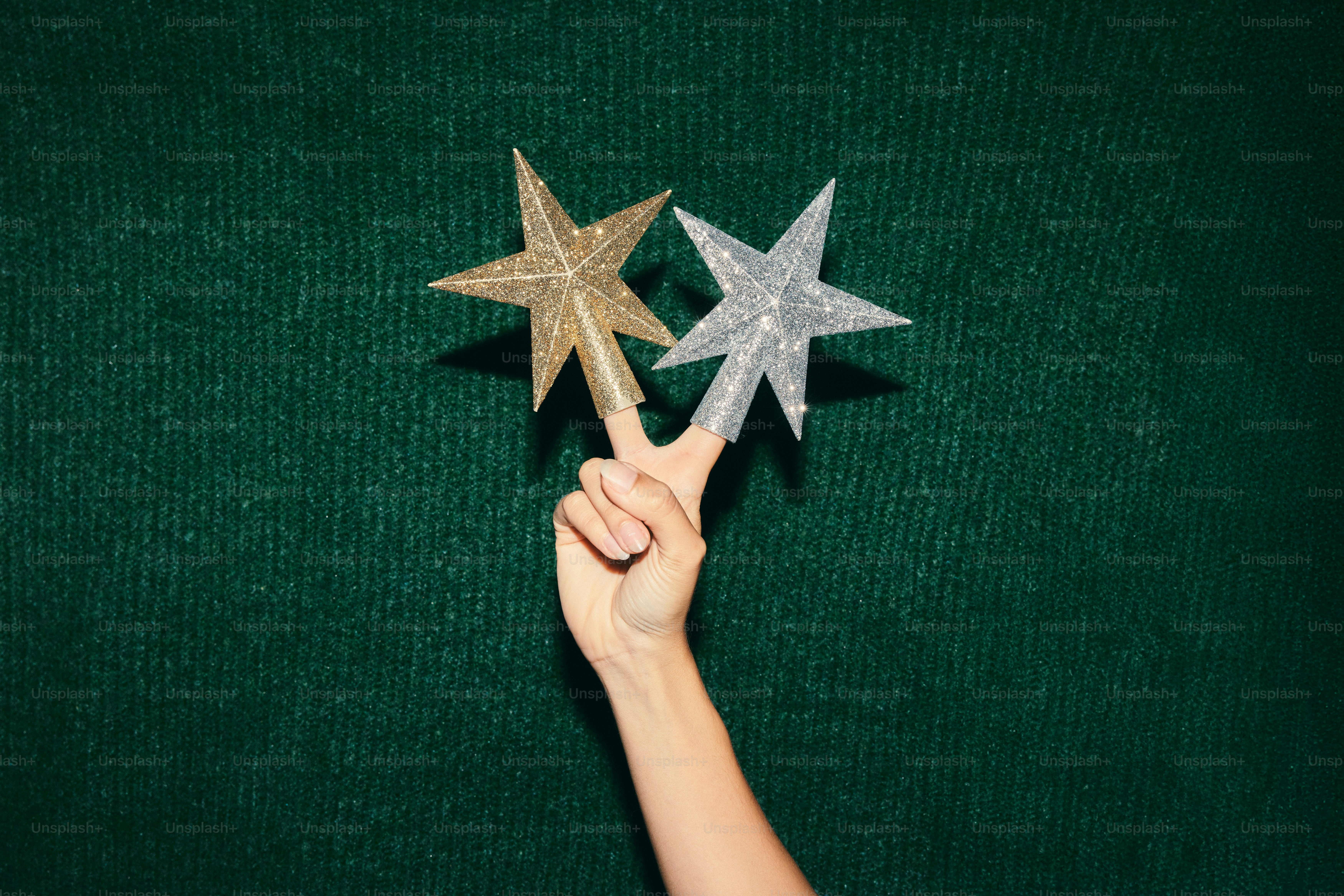 Hand holding two sparkly stars against green background