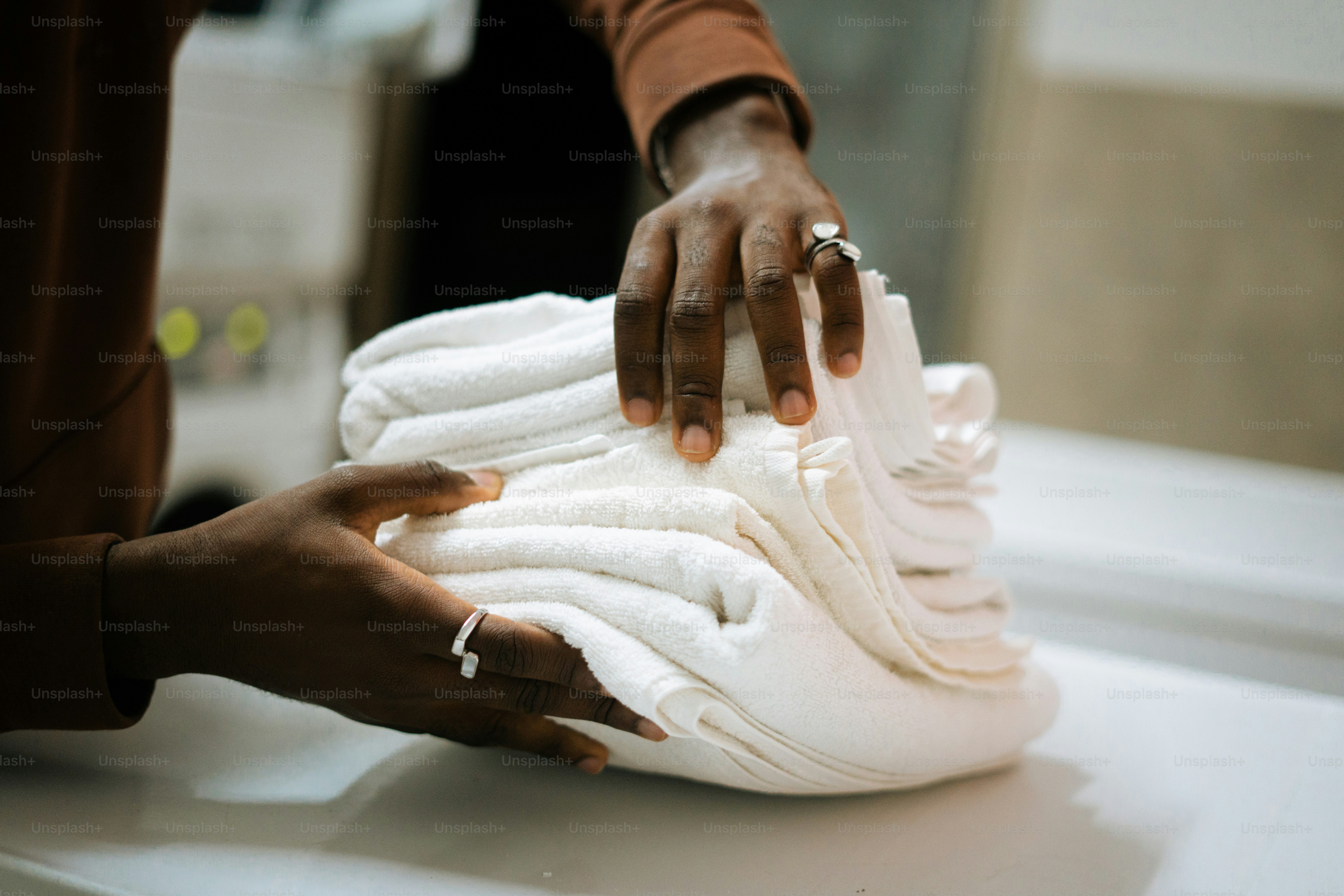 Hands folding a stack of clean white towels.