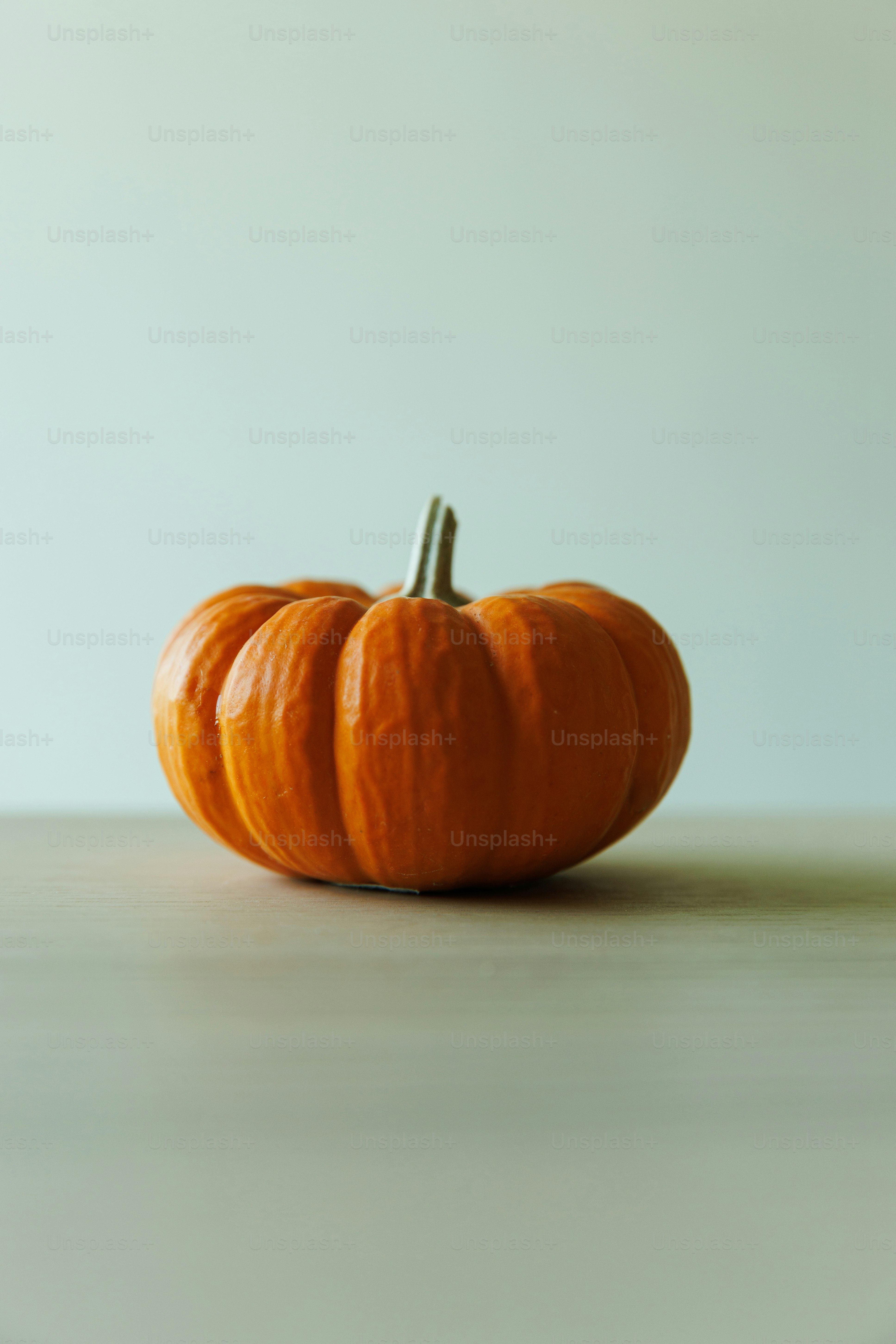 A single orange pumpkin on a light surface.