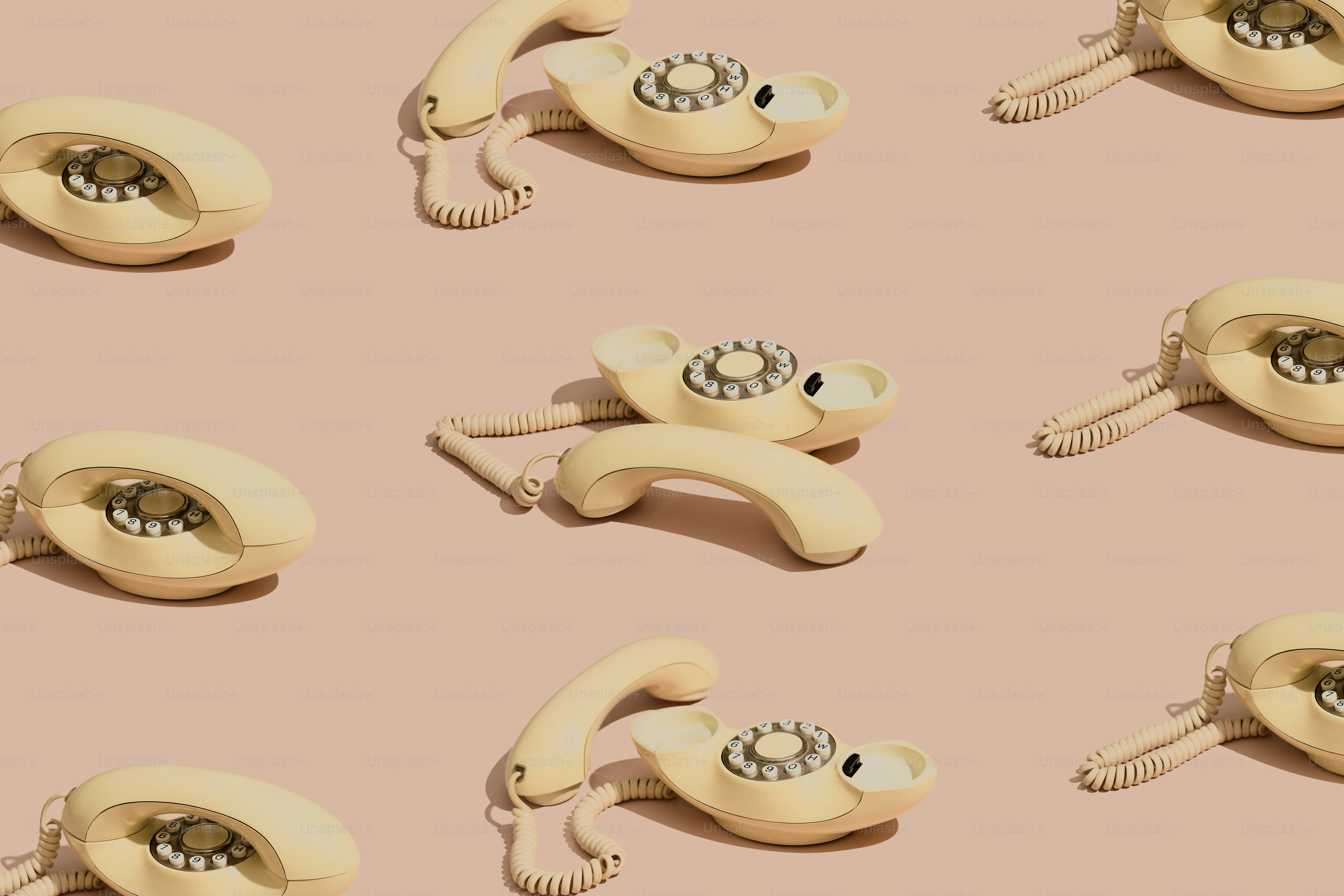 Teléfonos de disco retro dispuestos sobre un fondo rosa