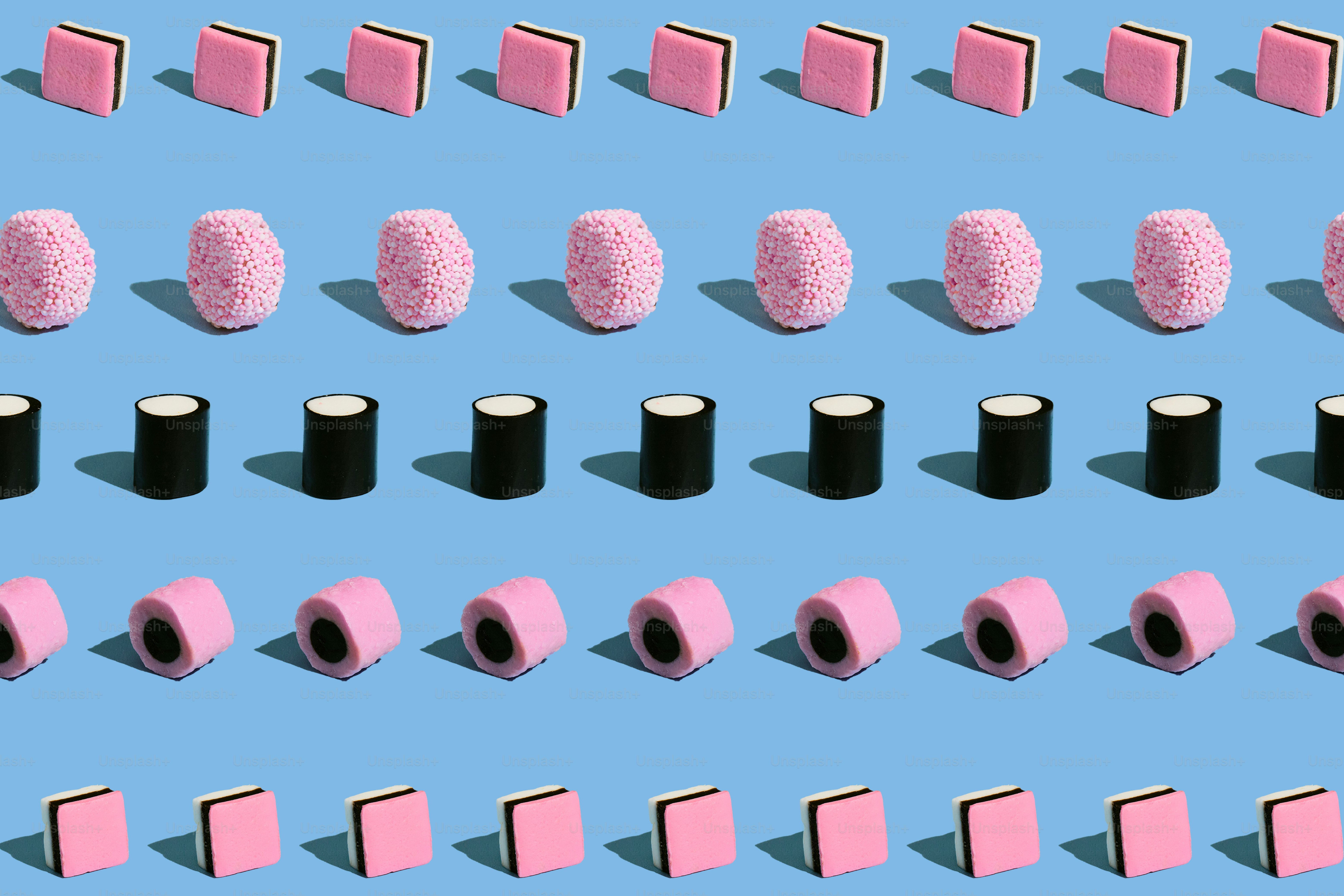 Rows of pink and black licorice candy on blue.