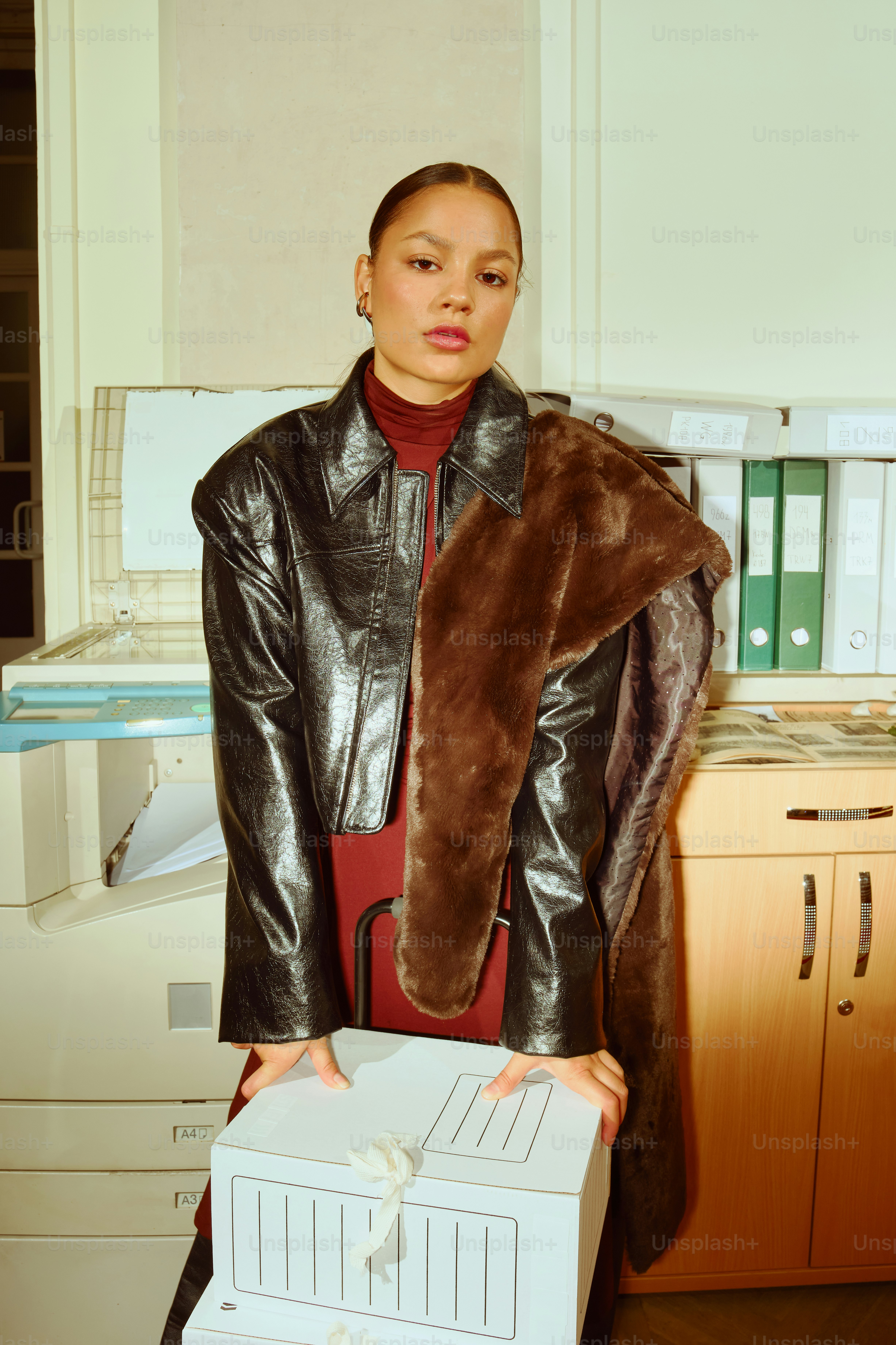 Woman in stylish outfit holding box in office