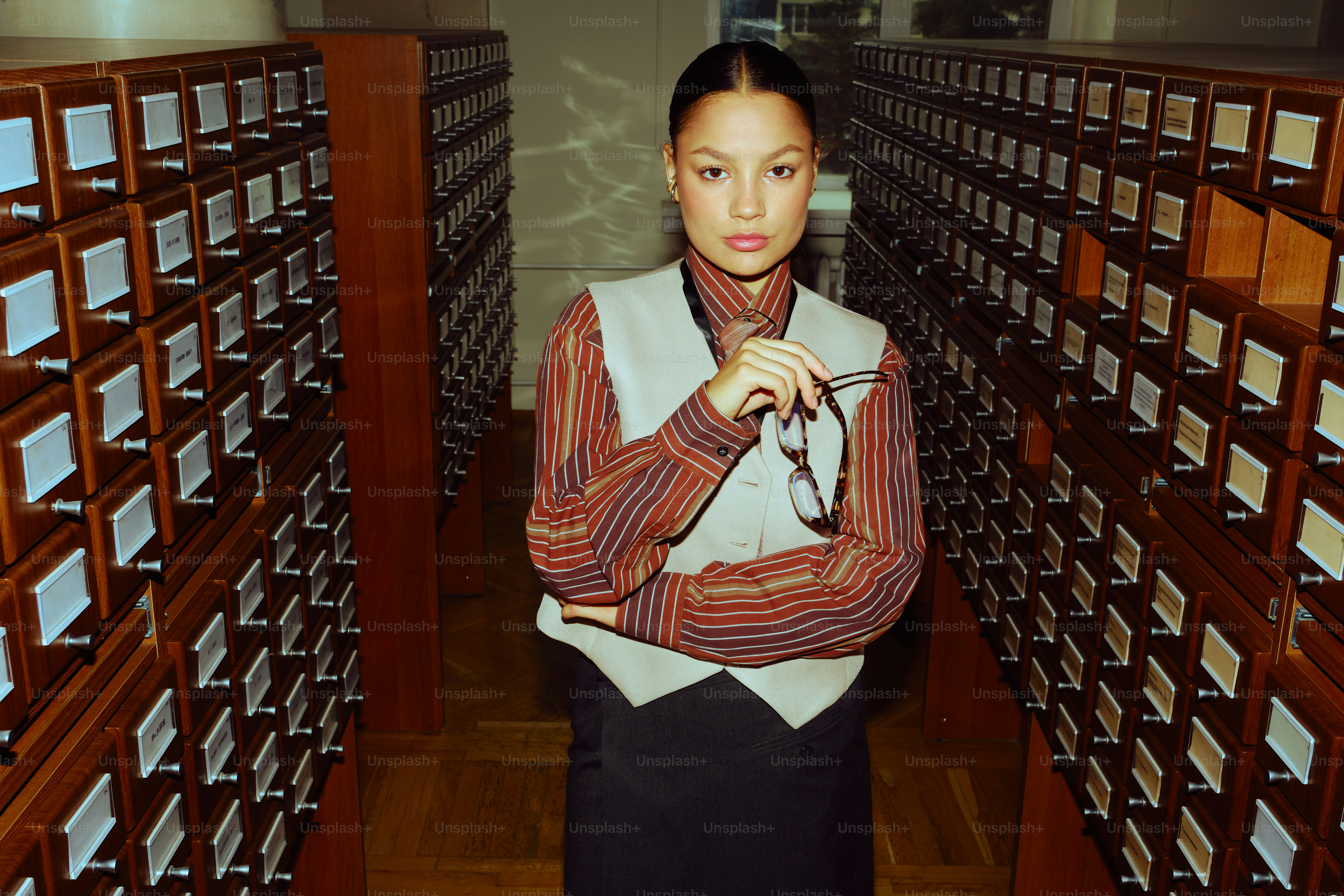 Woman holding glasses in a library card catalog