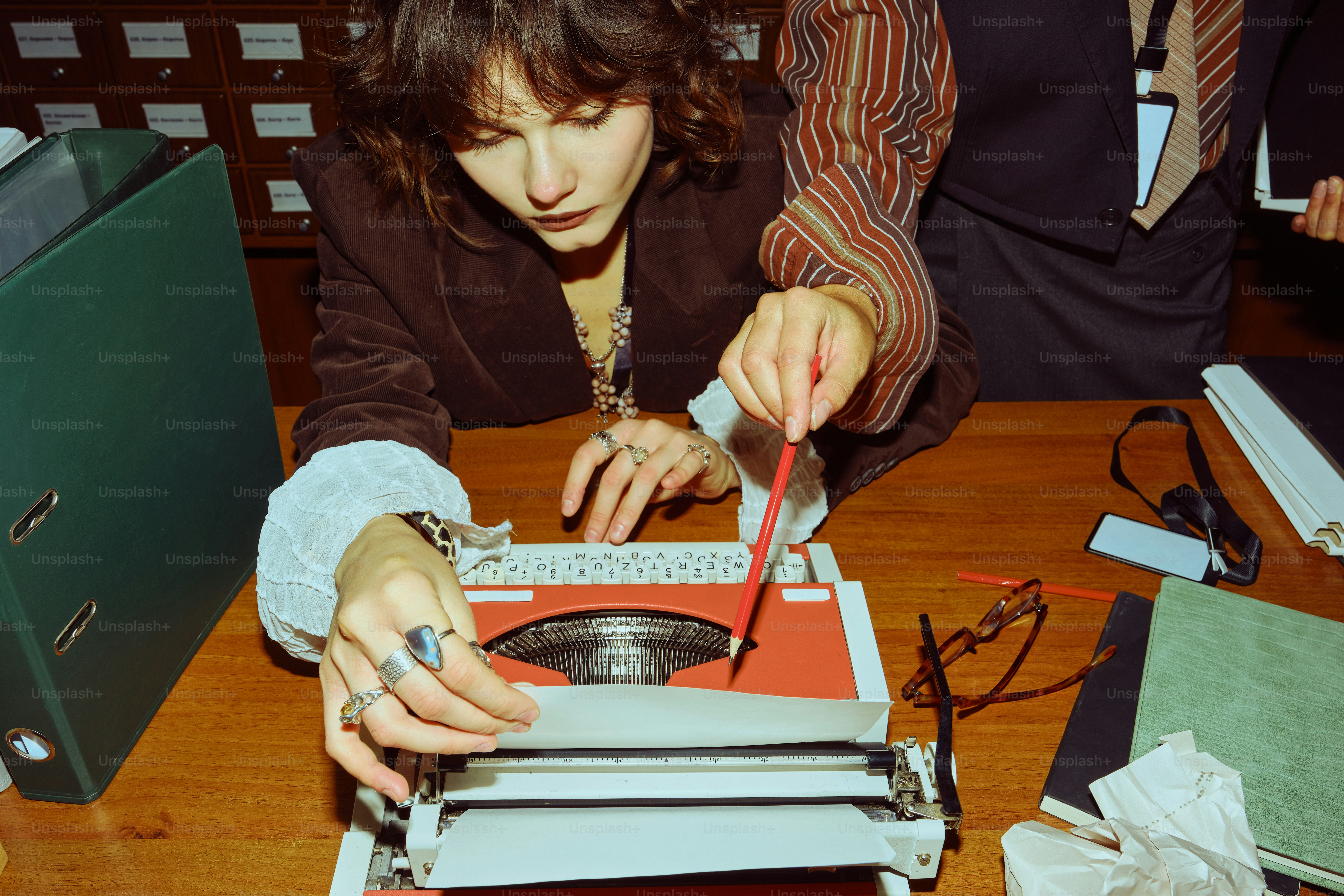 Woman using a vintage typewriter at a desk.