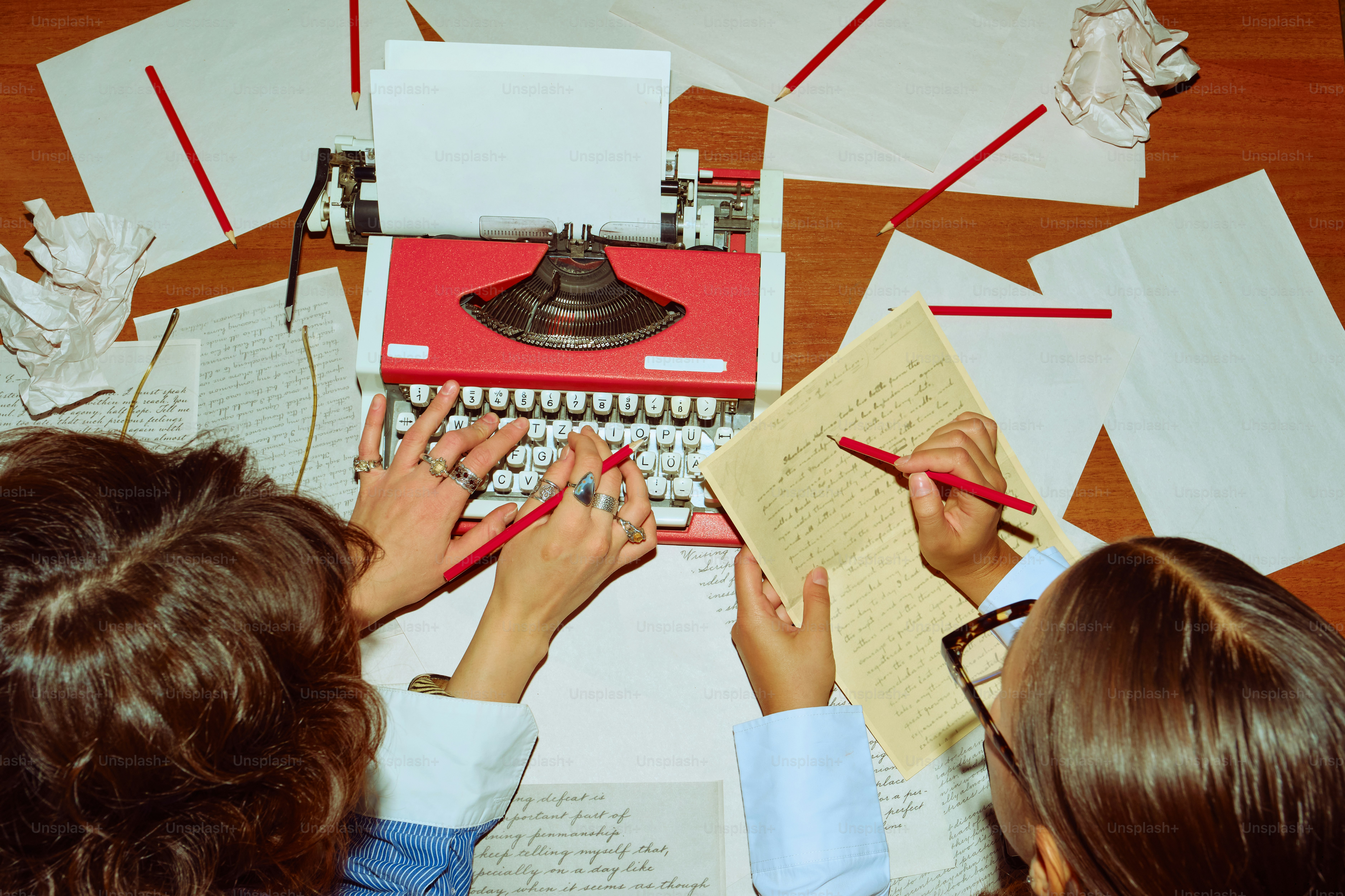 Two people typing on a vintage typewriter