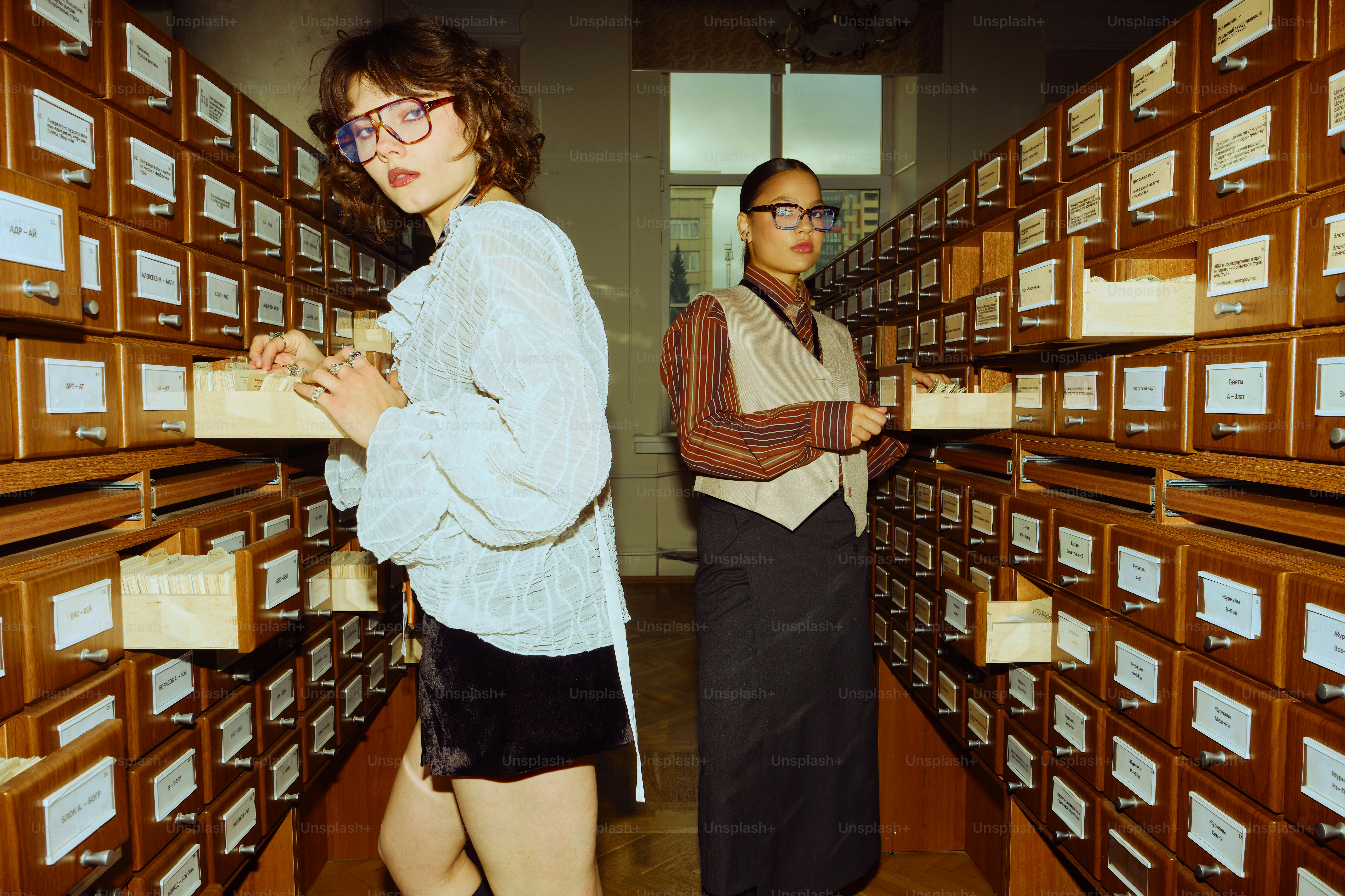 Two people in a library with card catalog drawers