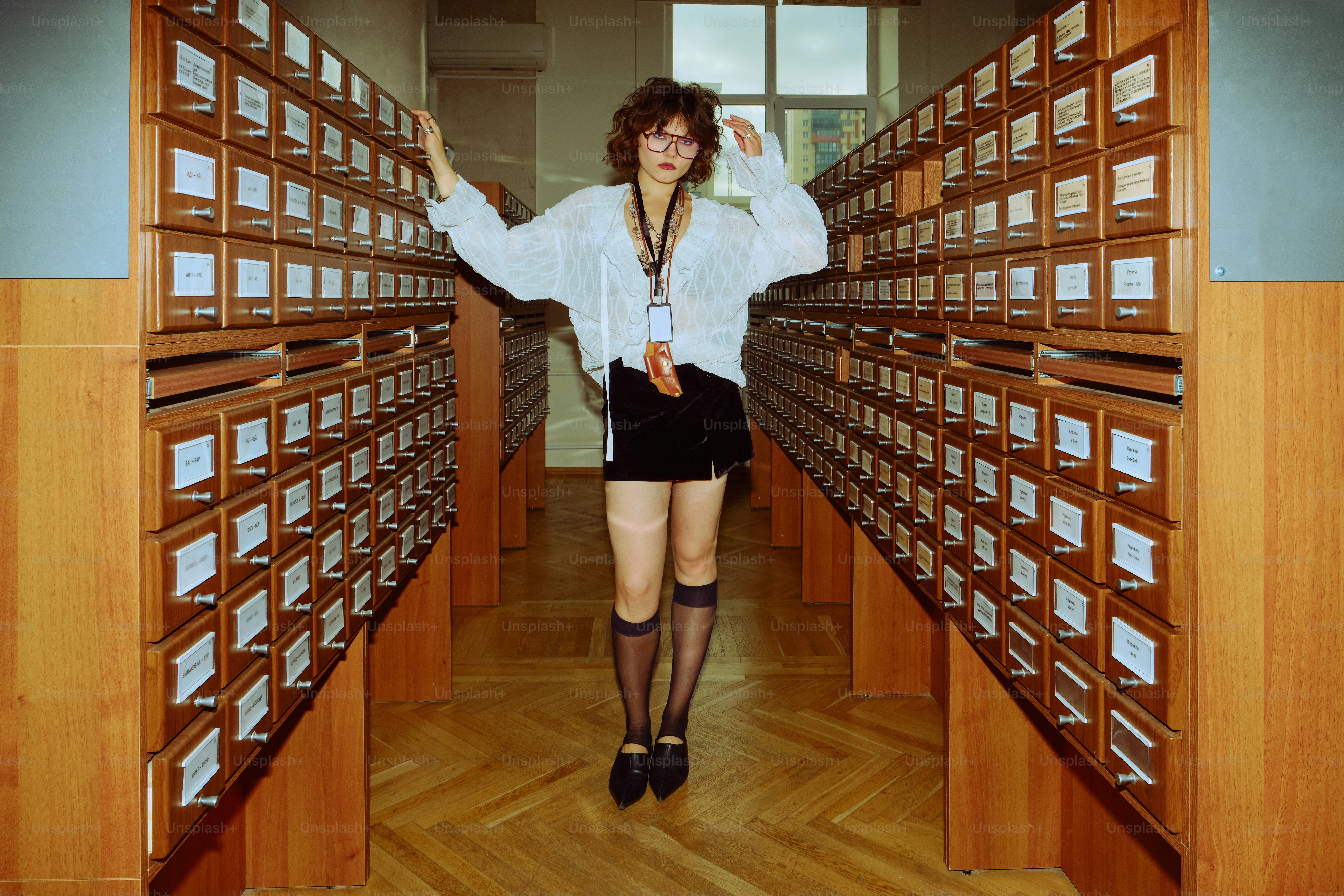 Woman standing between library card catalog drawers