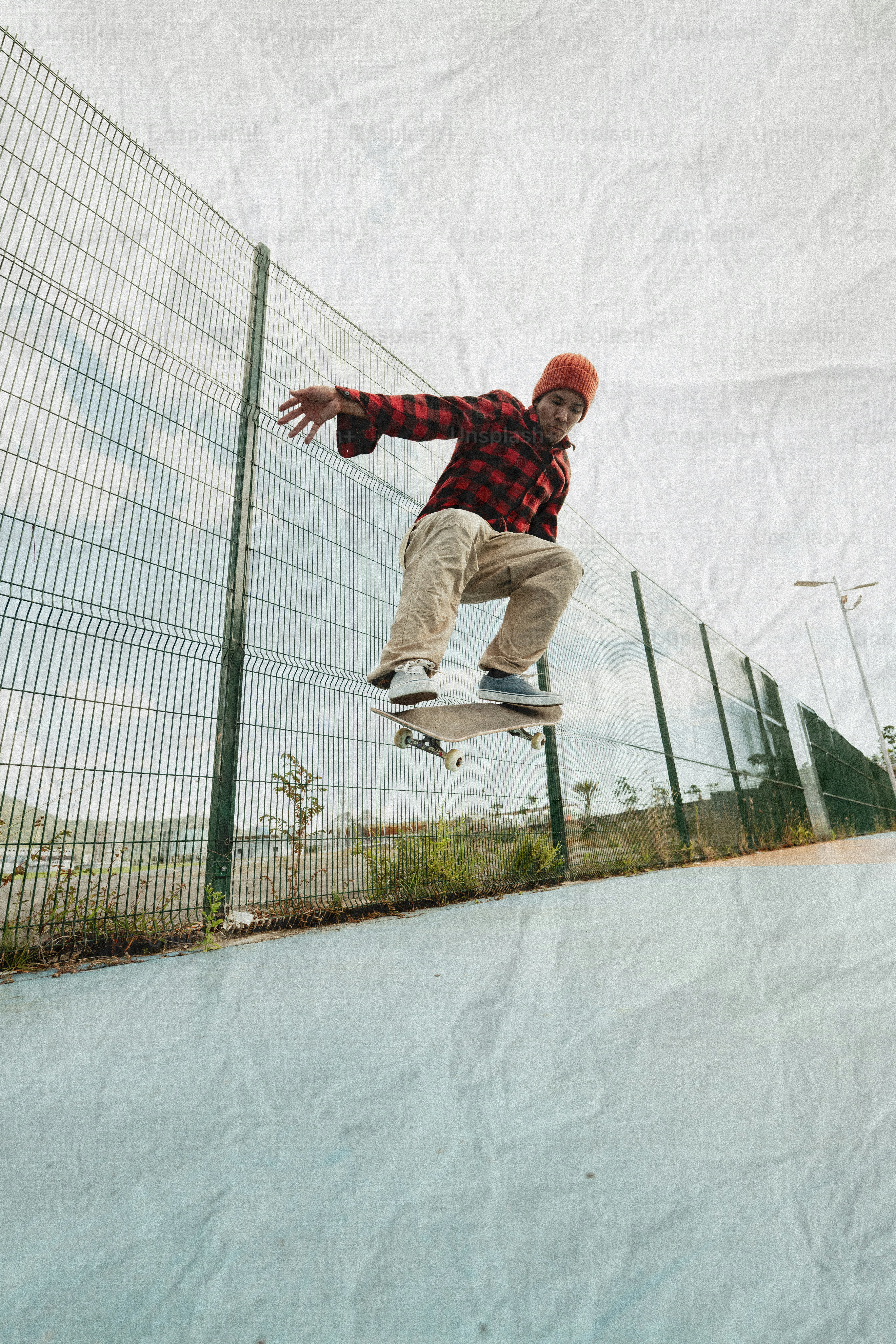 Skateboarder jumping in the air near a fence