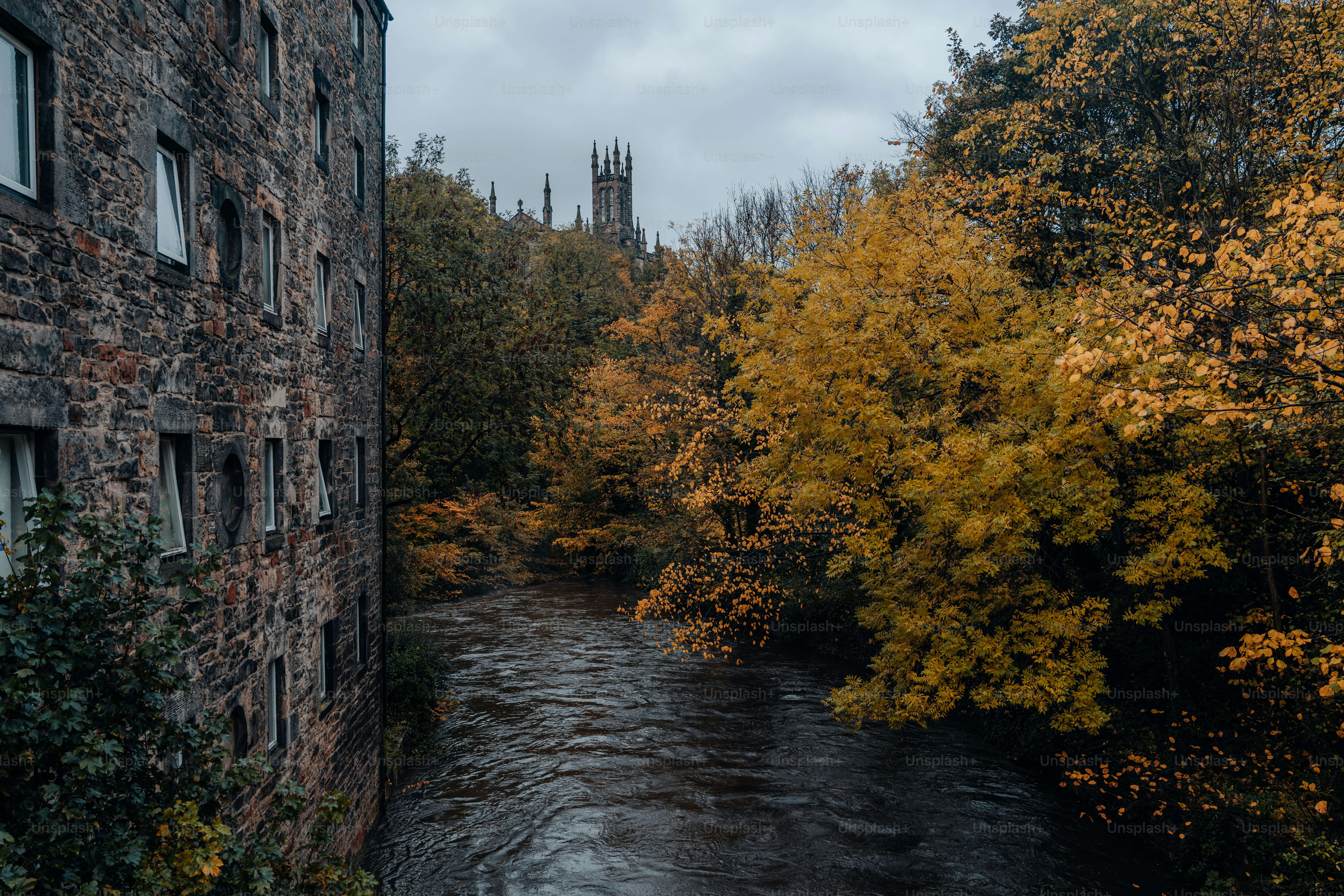 River flows past old building with autumn trees