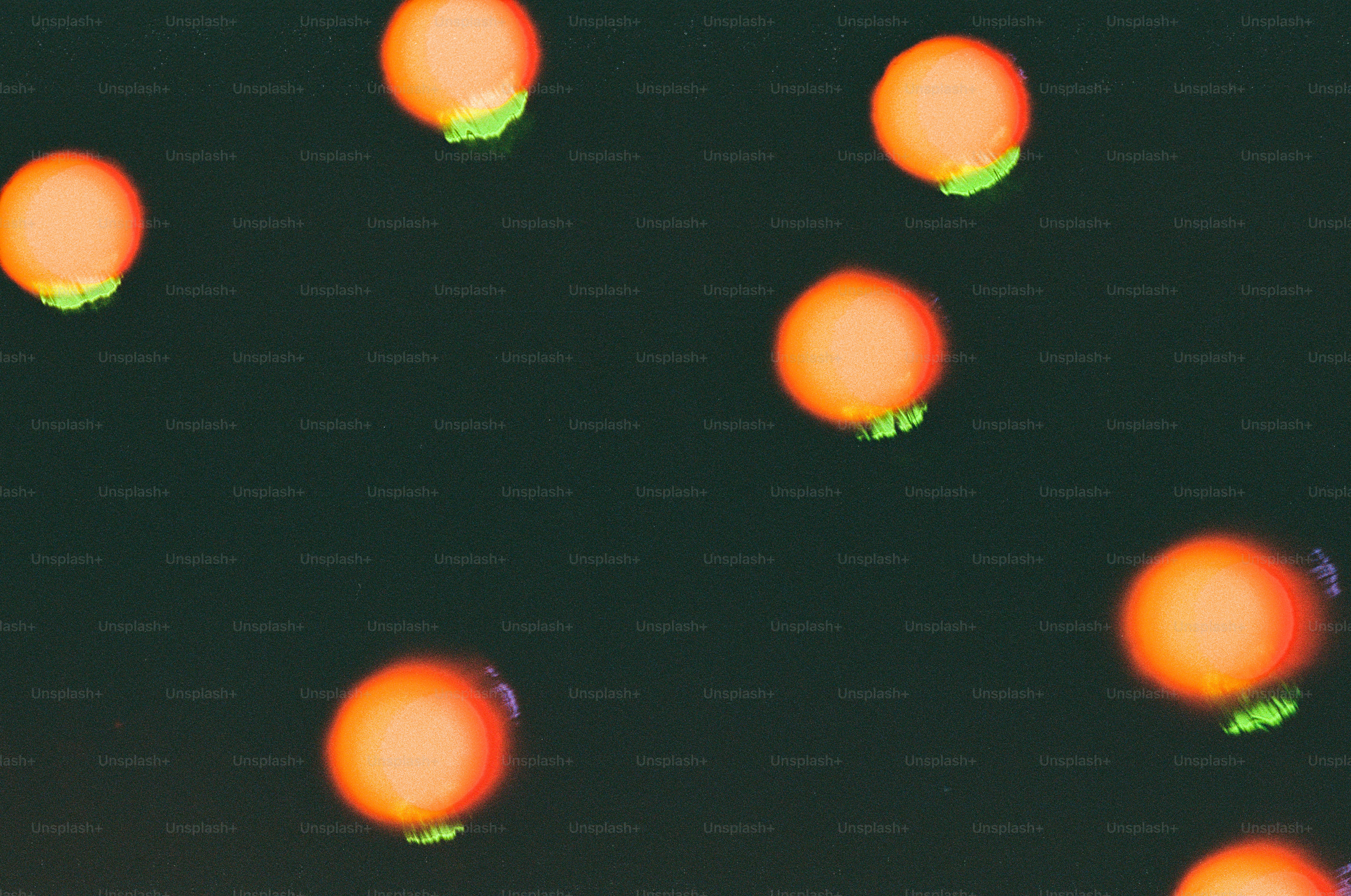 Orange spheres with green bottoms on dark background.