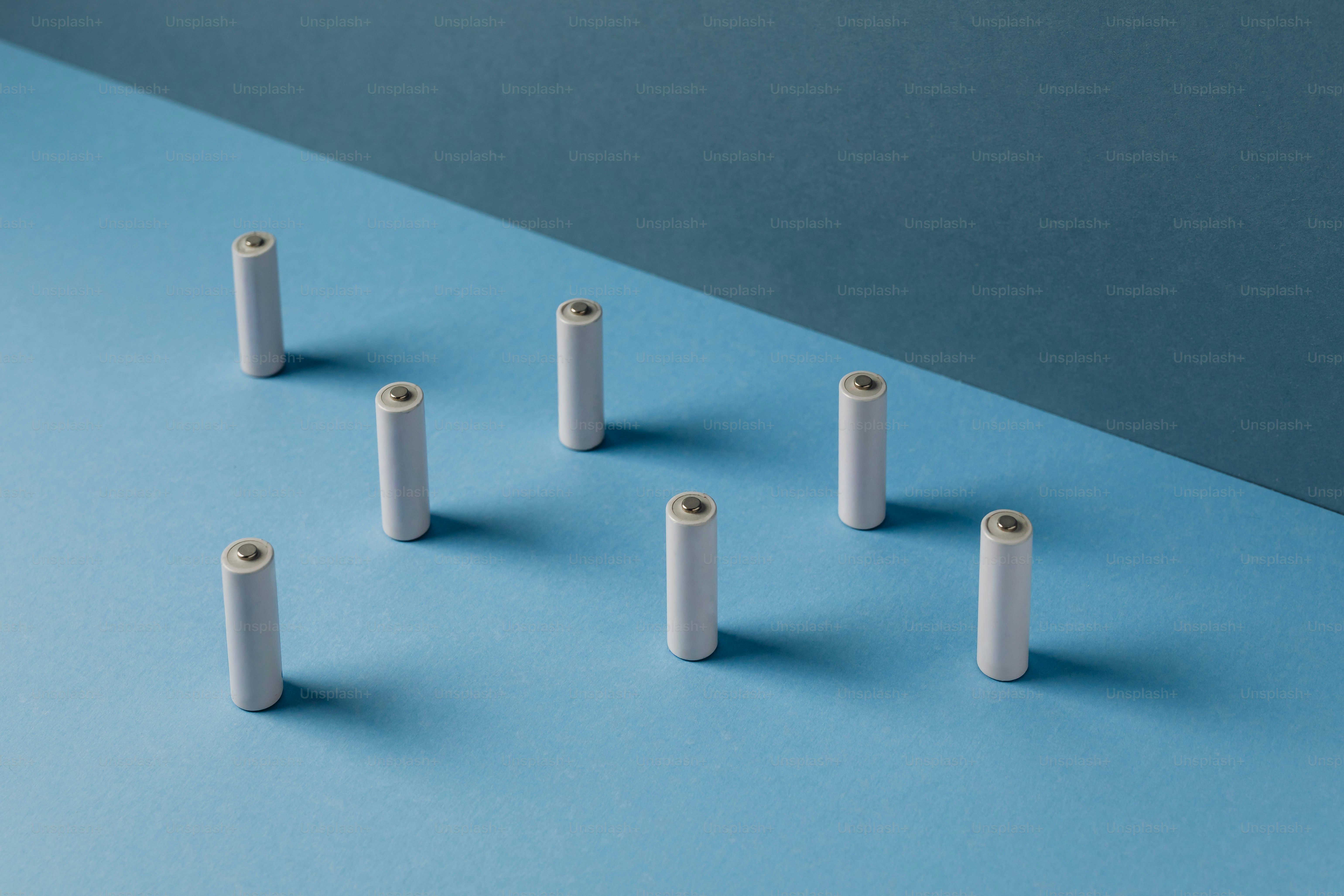 Several white batteries arranged on a blue surface