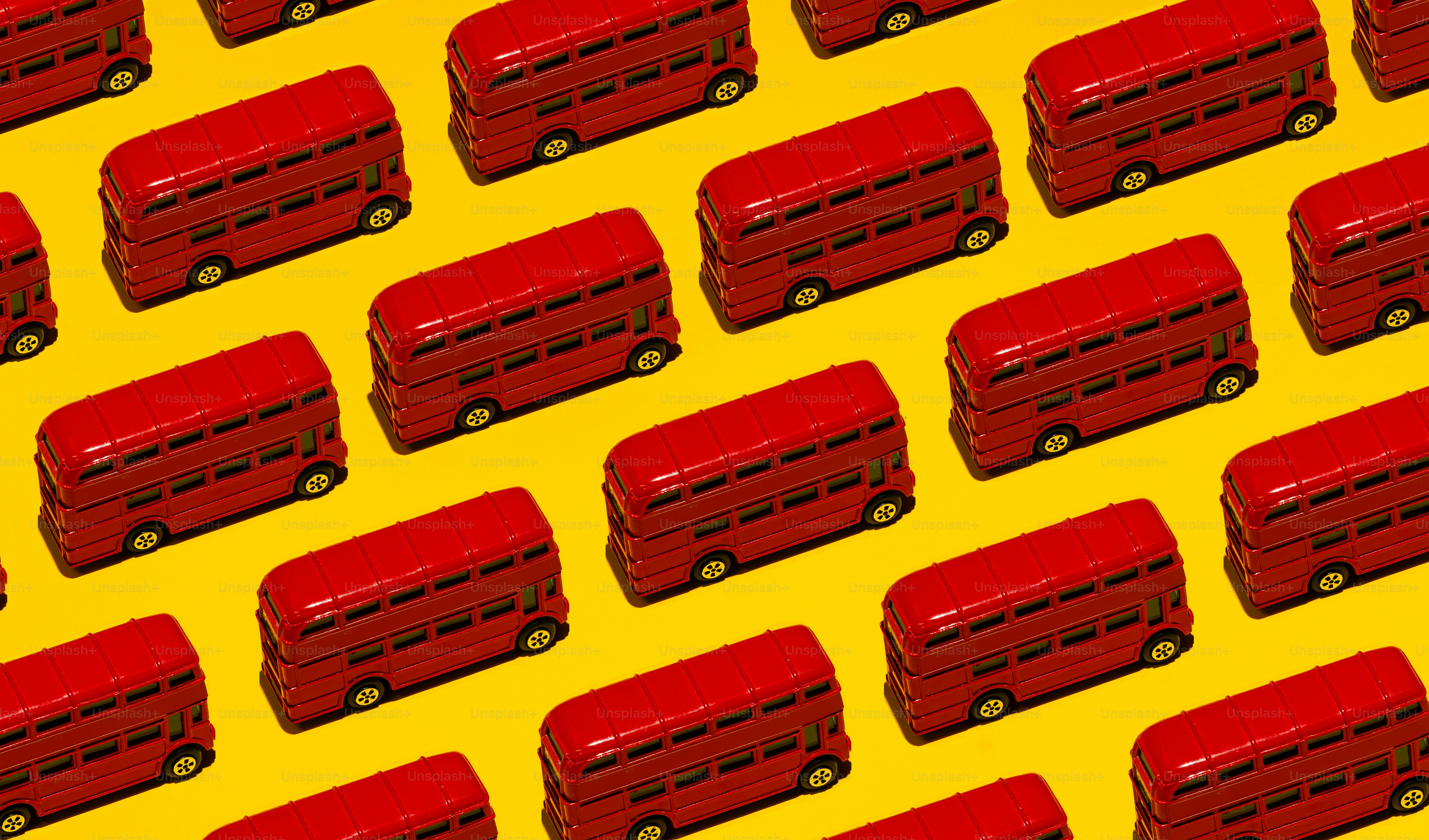 Red double-decker buses arranged on yellow background
