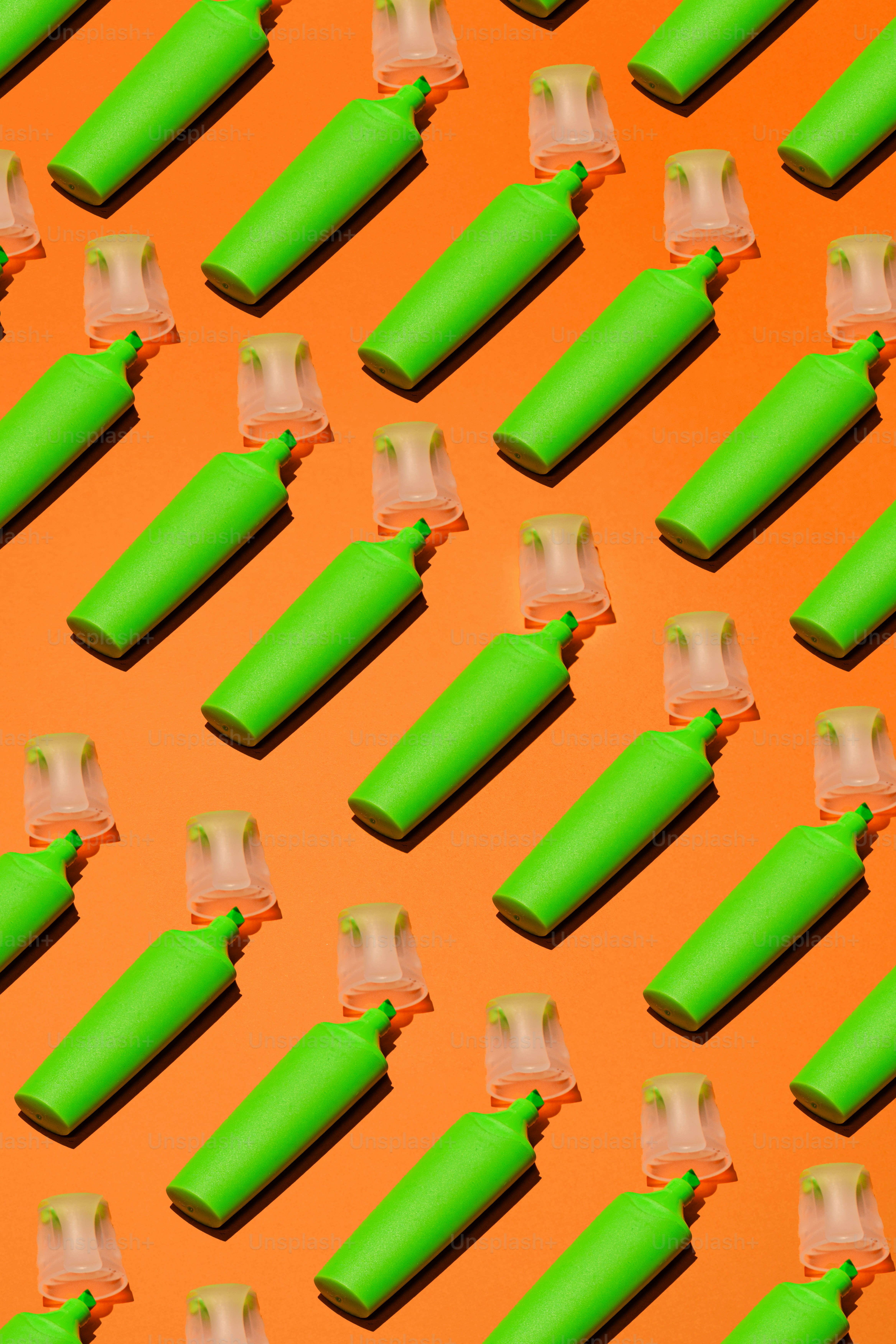 Green highlighters arranged on an orange background