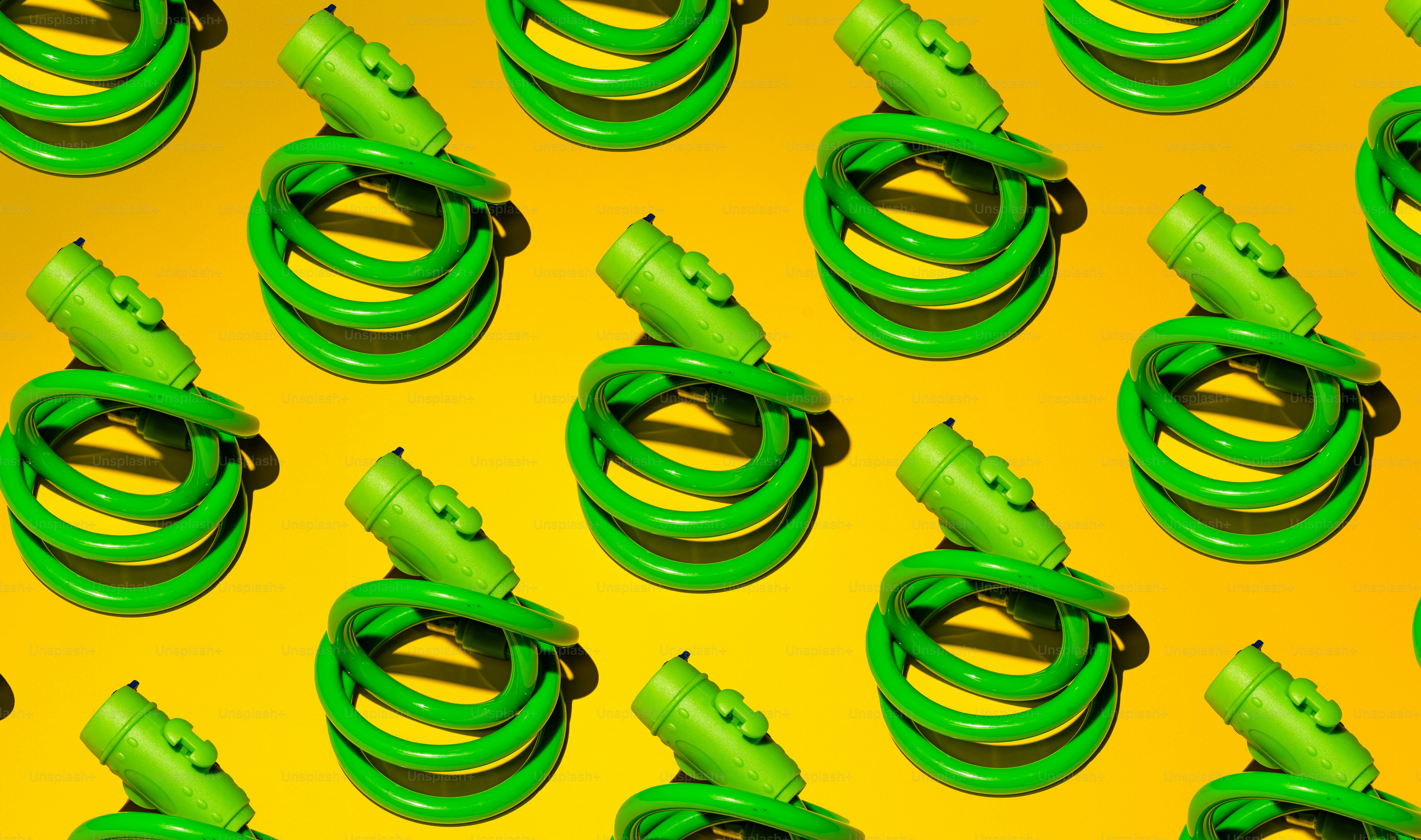 Green coiled cables with plugs on yellow background