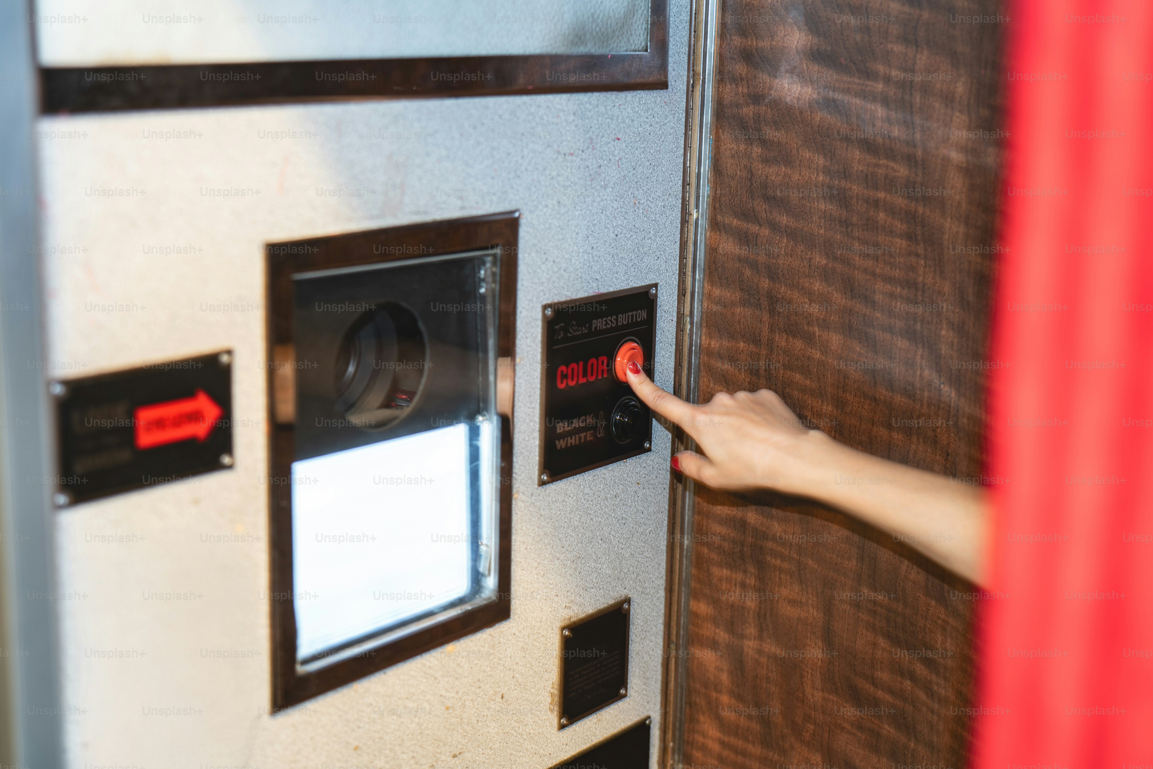 A mão pressiona o botão na máquina da cabine da foto