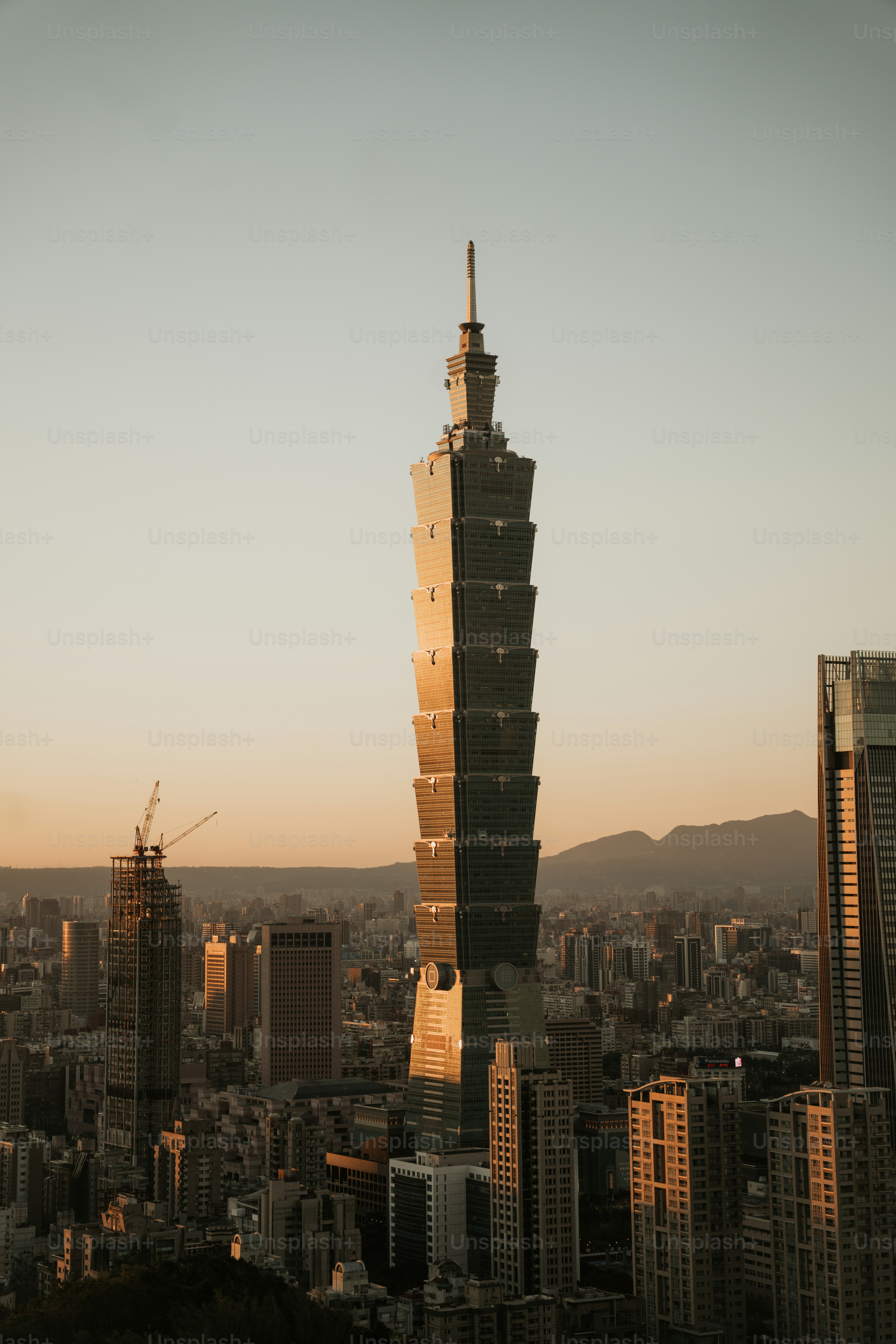 Skyscraper against a warm sunset sky over cityscape.