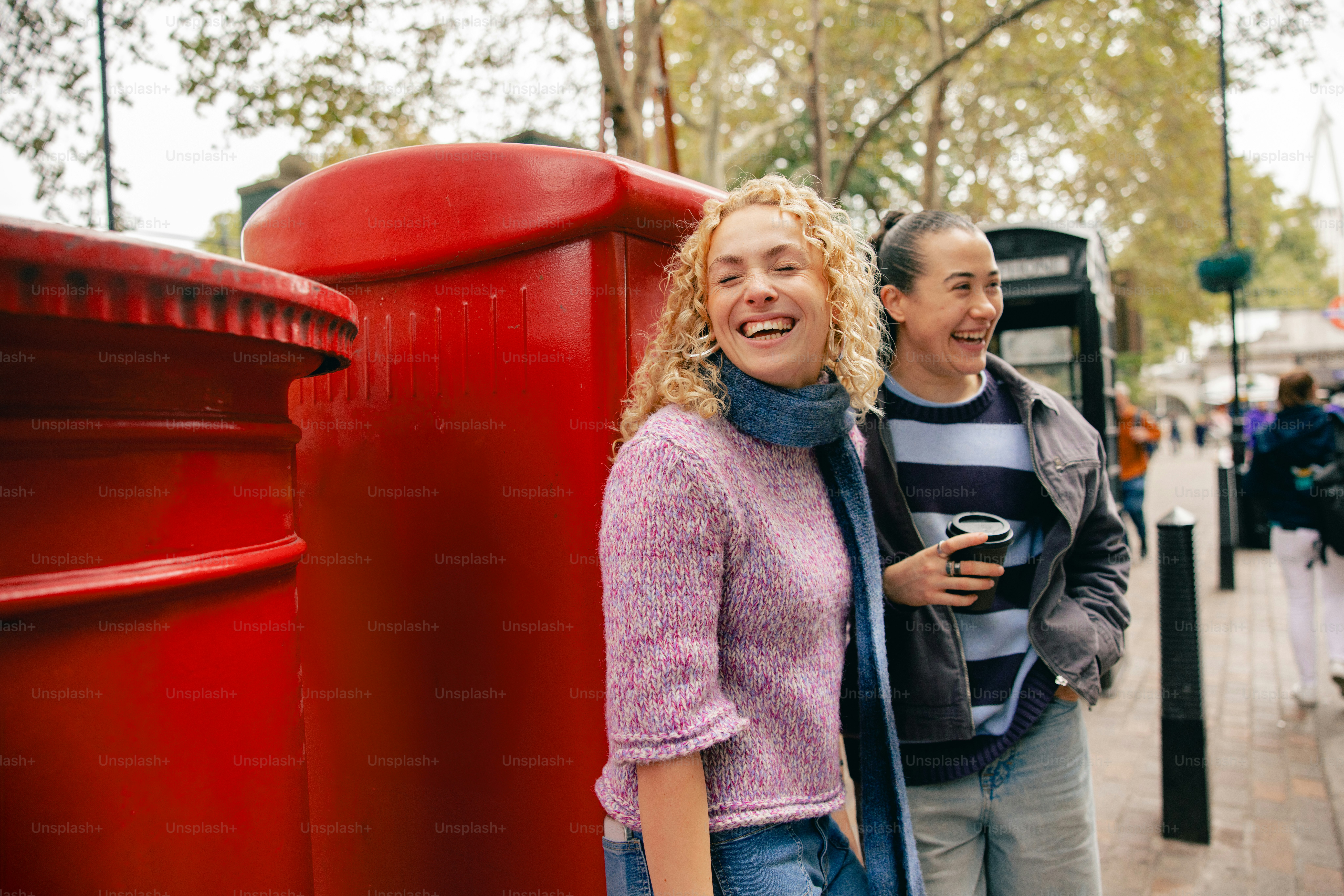 Two women laughing near red post boxes