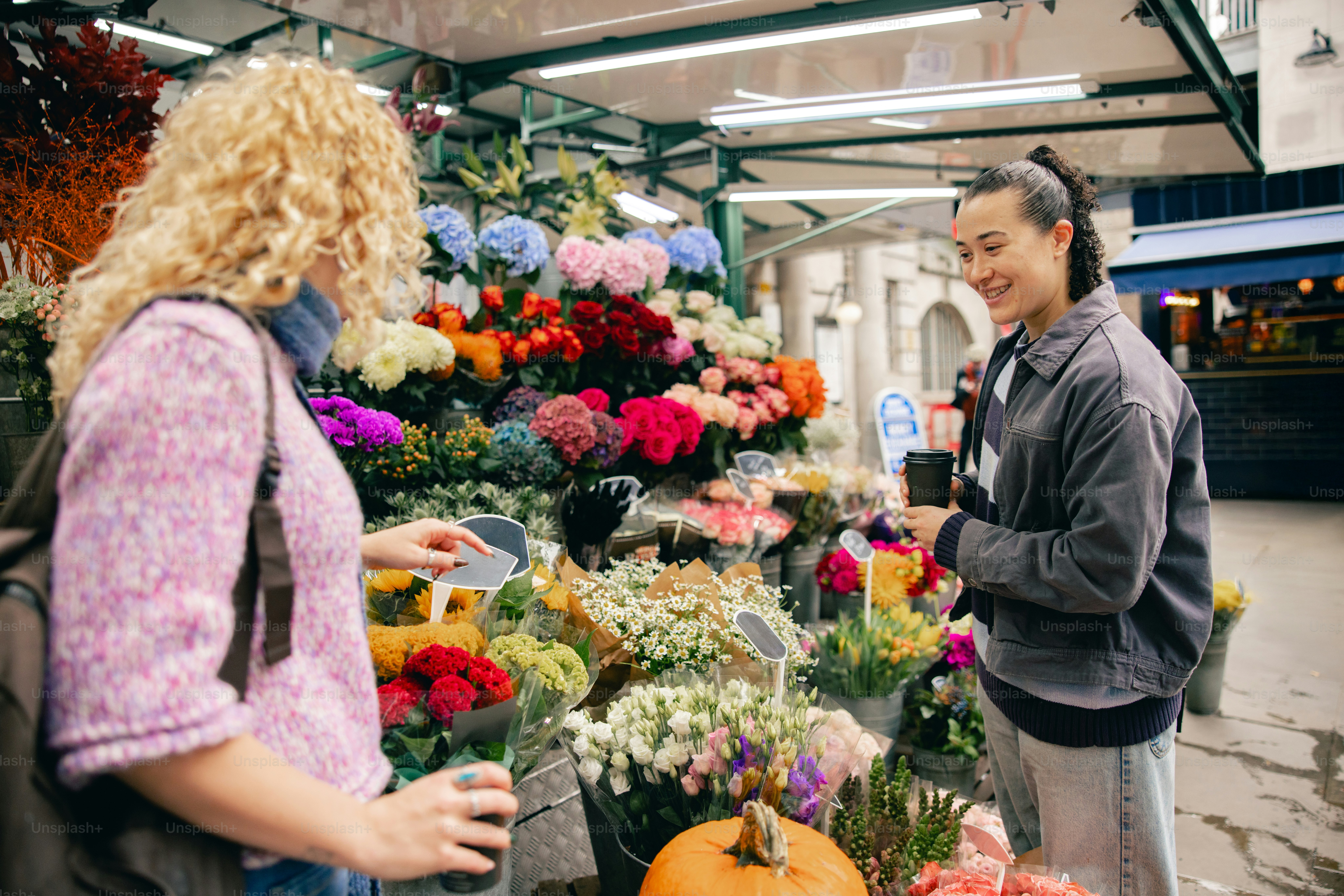 Two women at a flower stall with colorful blooms