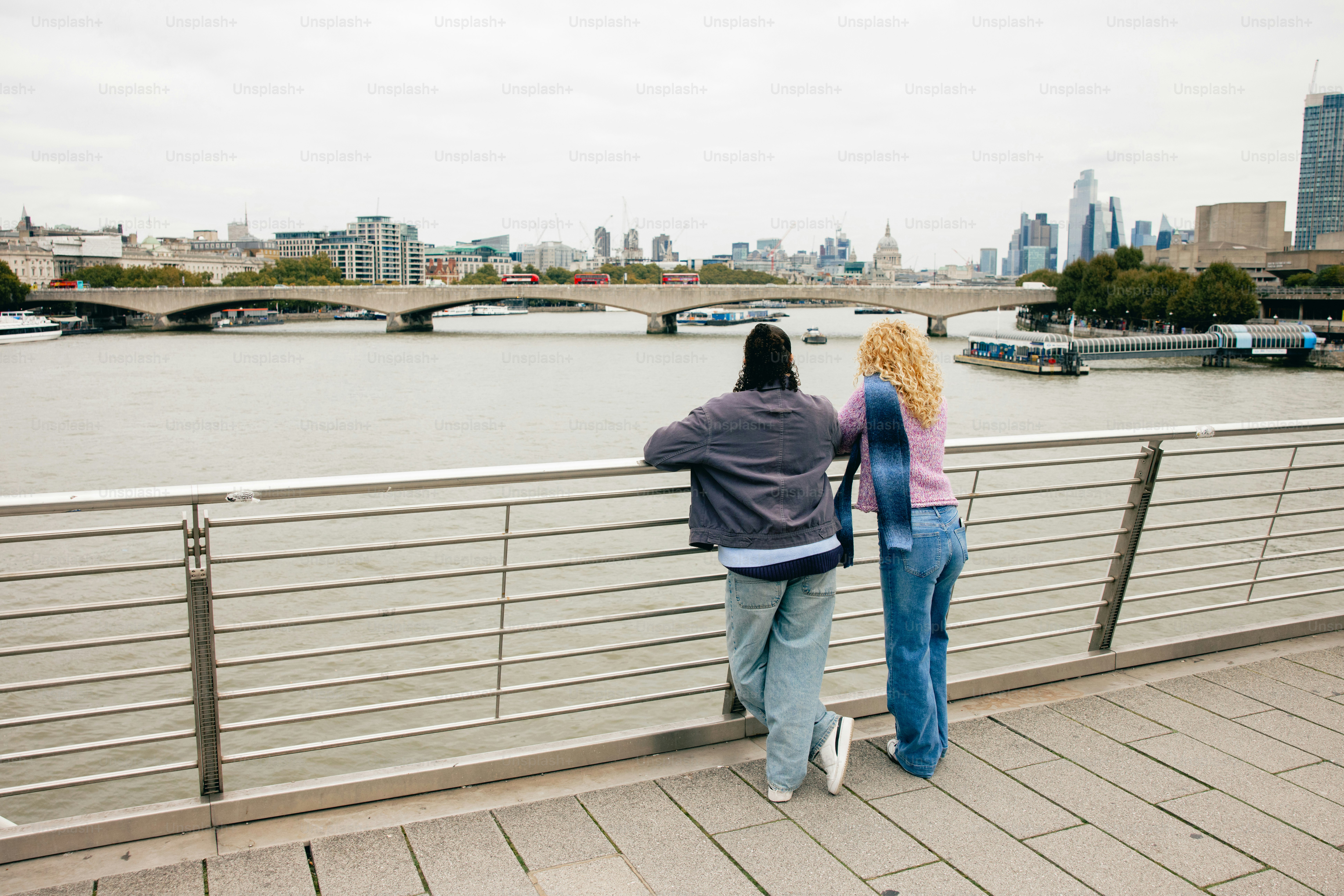 Two people look at city skyline across river