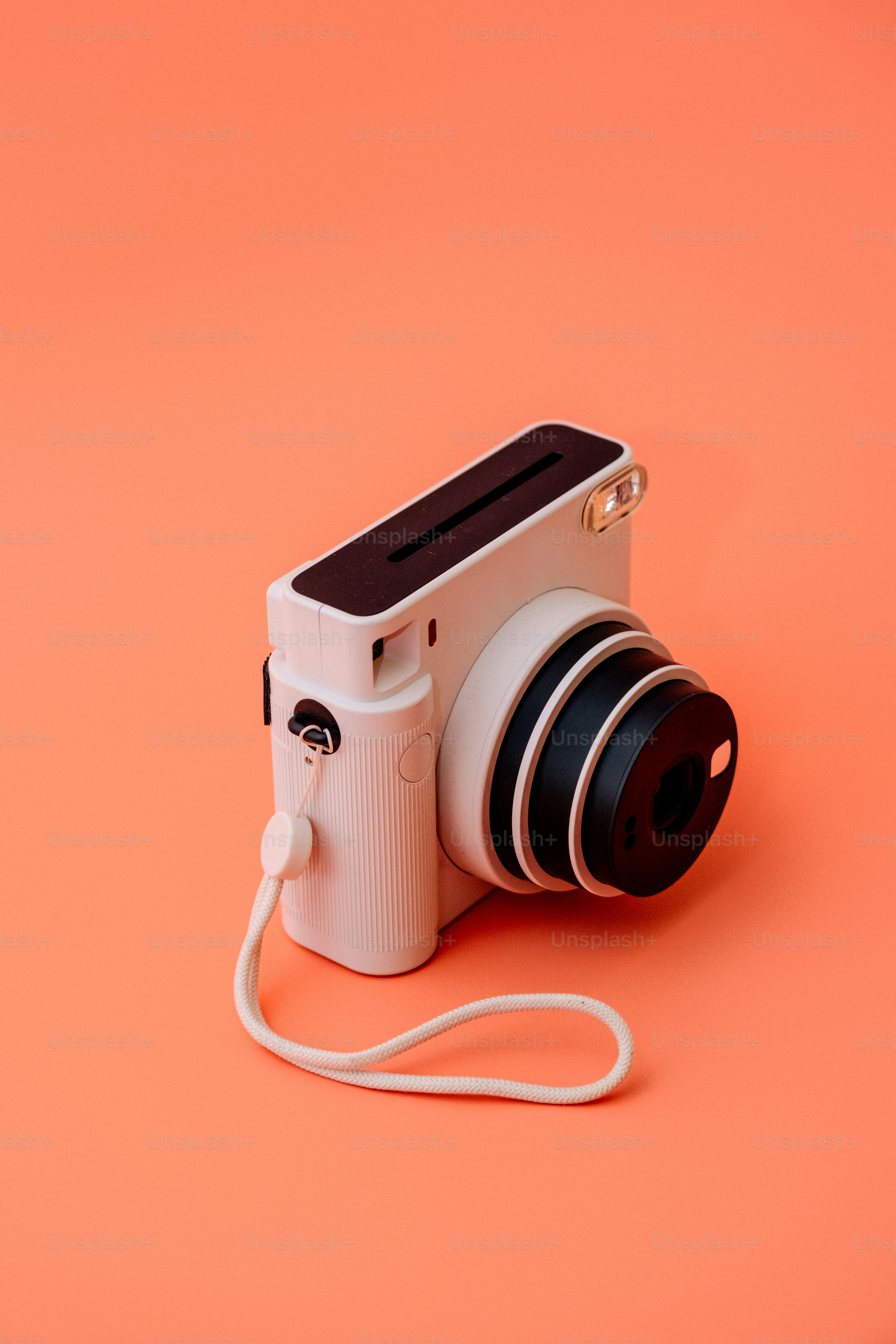 Eine weiße Sofortbildkamera auf orangefarbenem Hintergrund