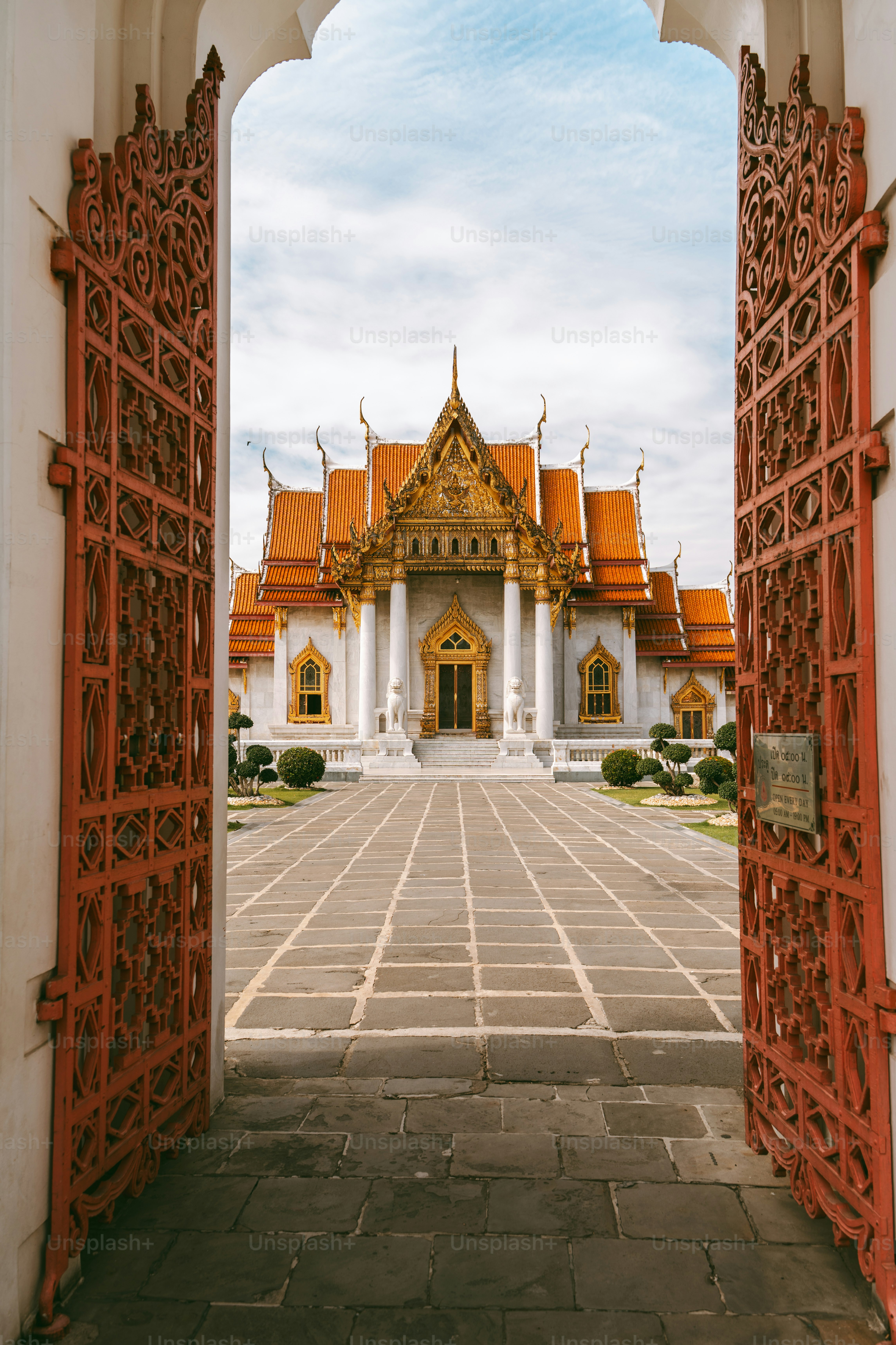Ornate red gates open to a grand temple building.