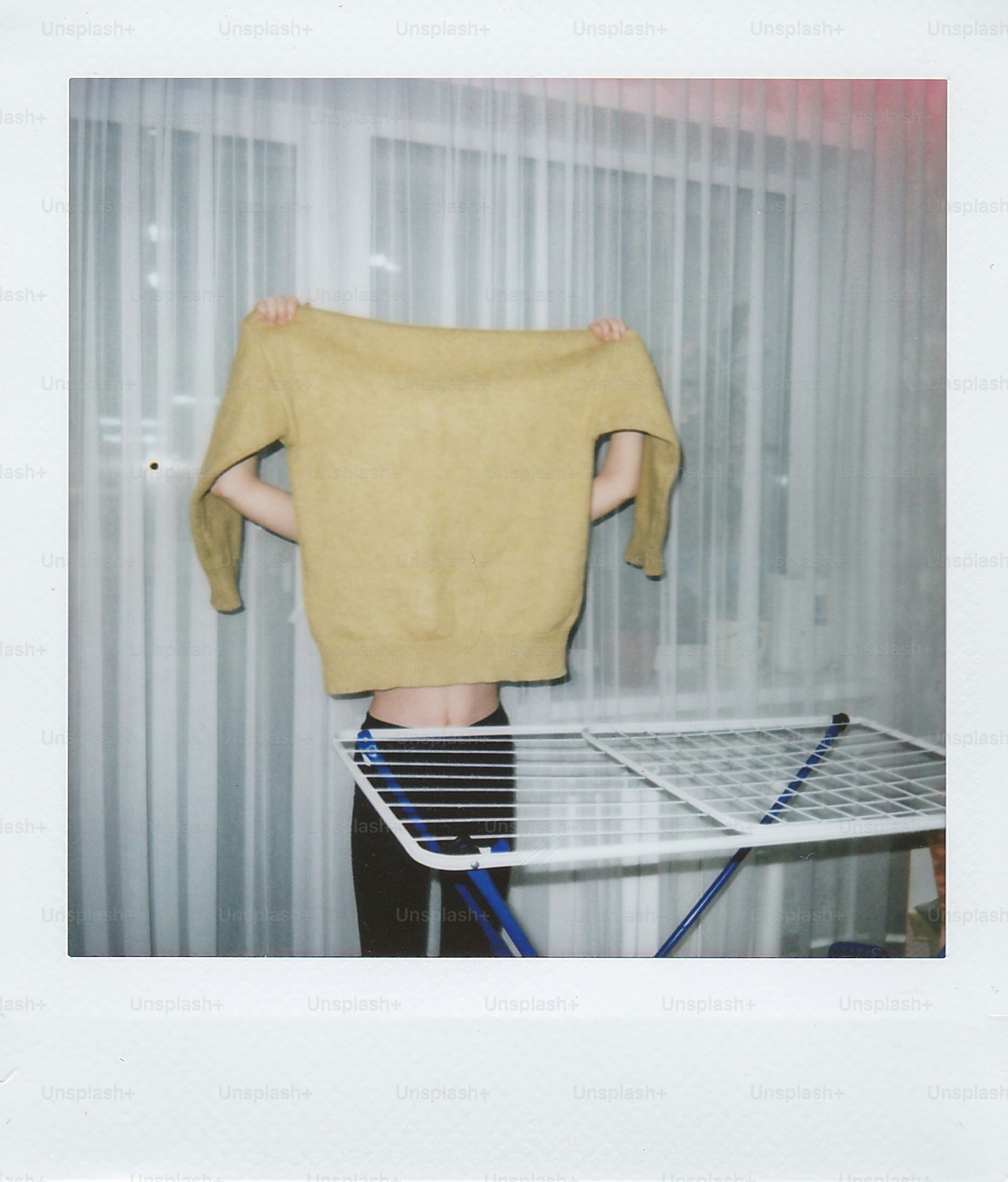Person holding yellow sweater over head