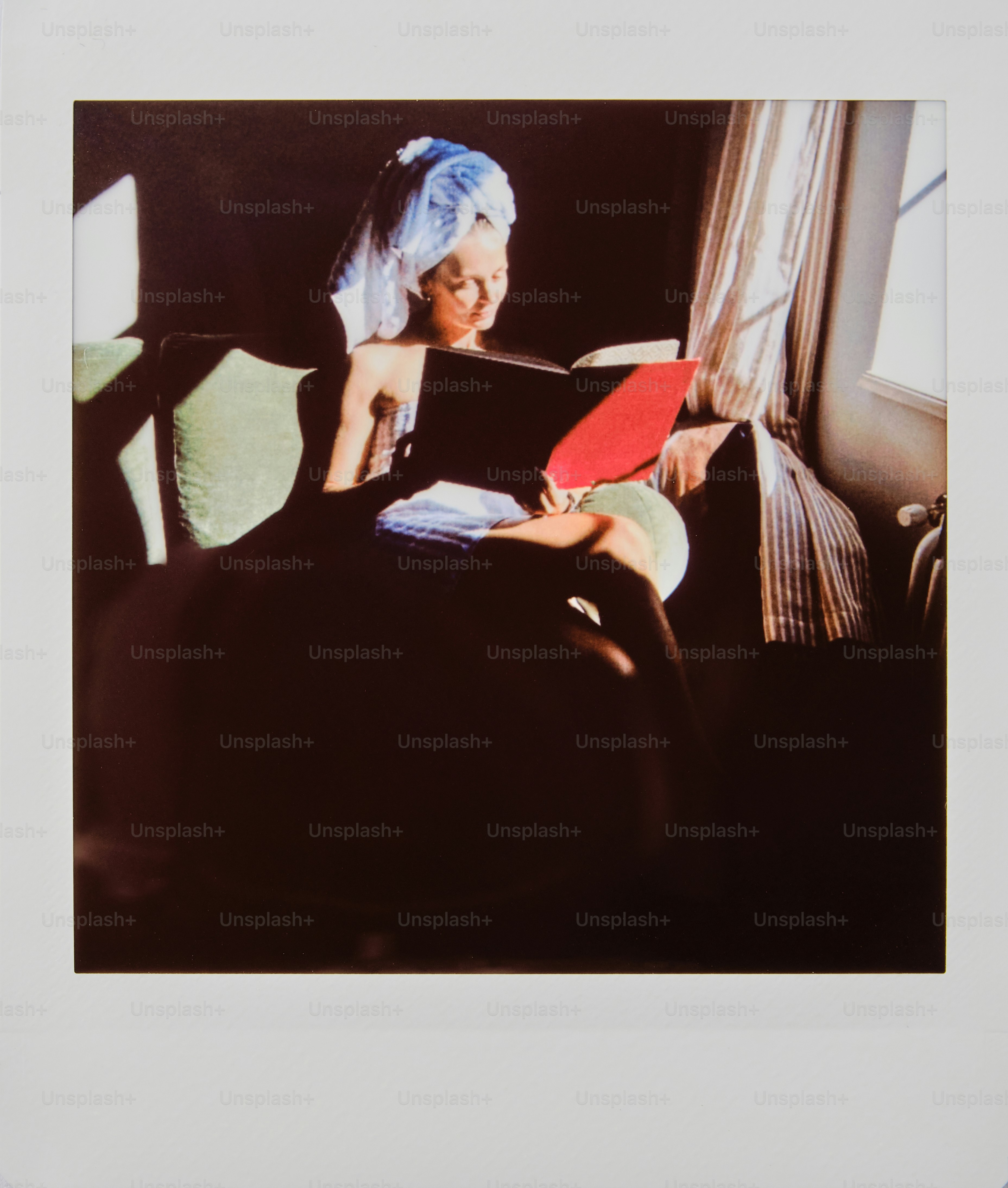 頭にタオルをかぶせて本を読んでいる女性。