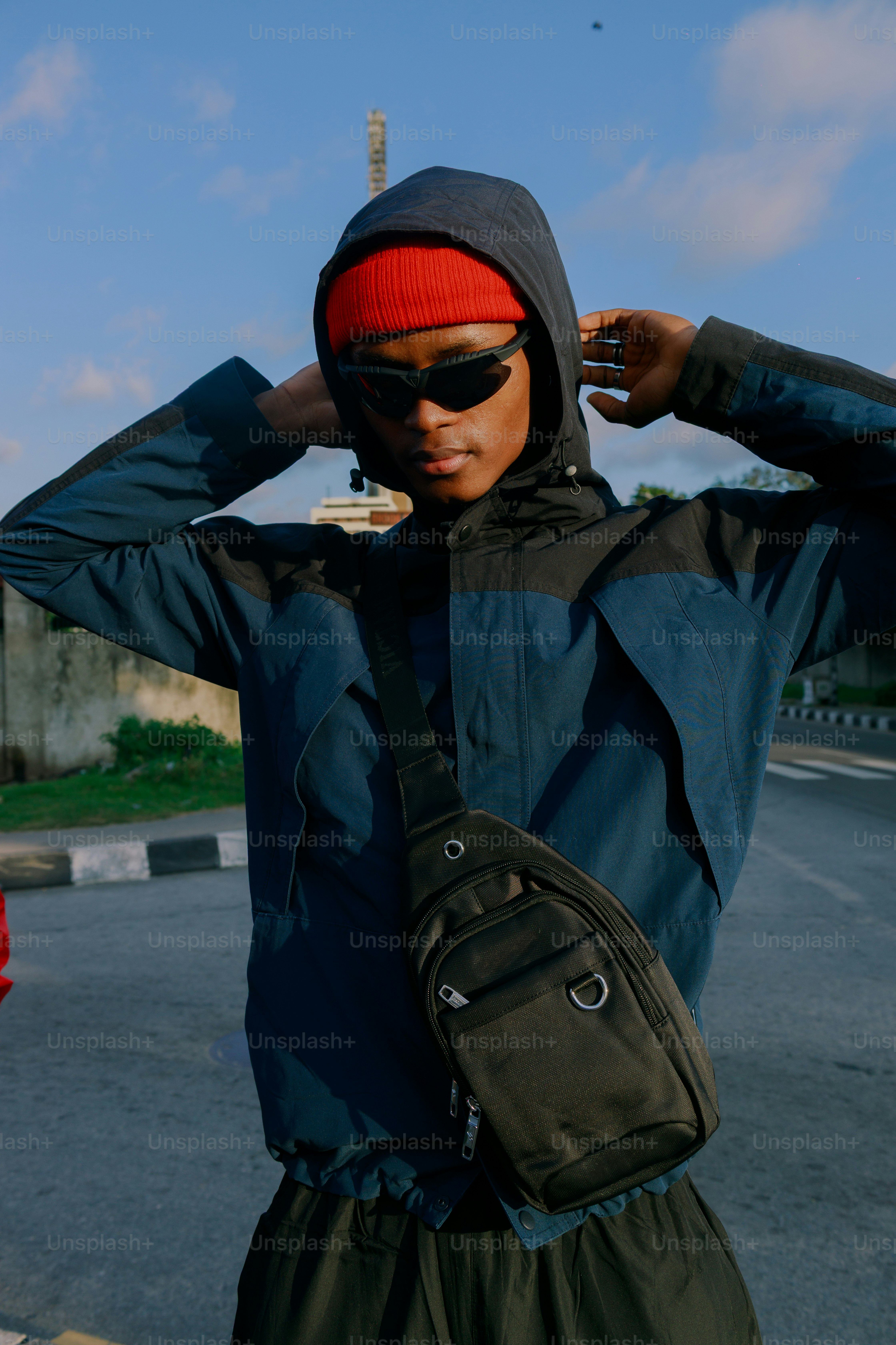 Young man wearing sunglasses and beanie adjusts hood