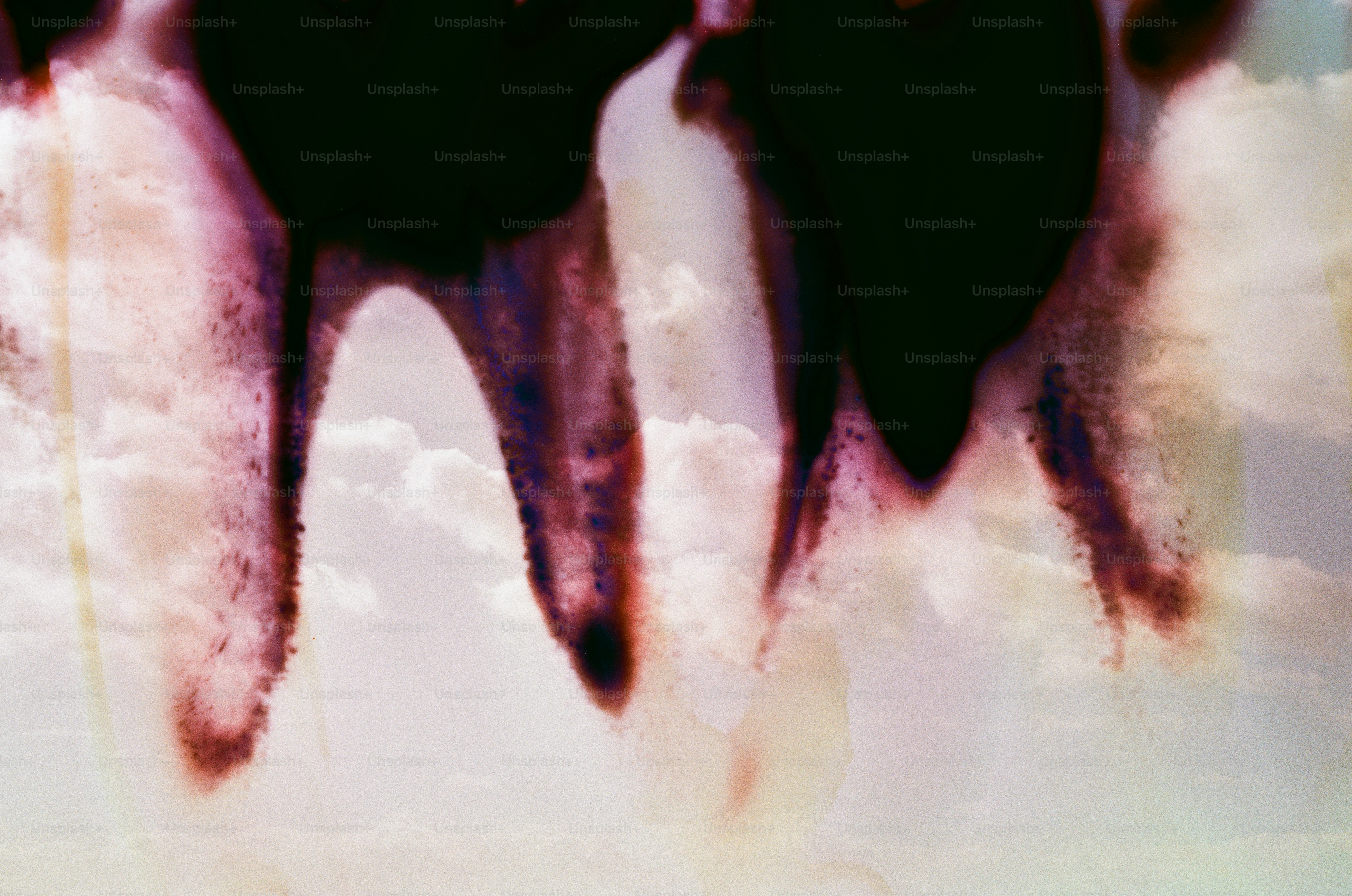 Abstract dark shapes with purple hues over clouds