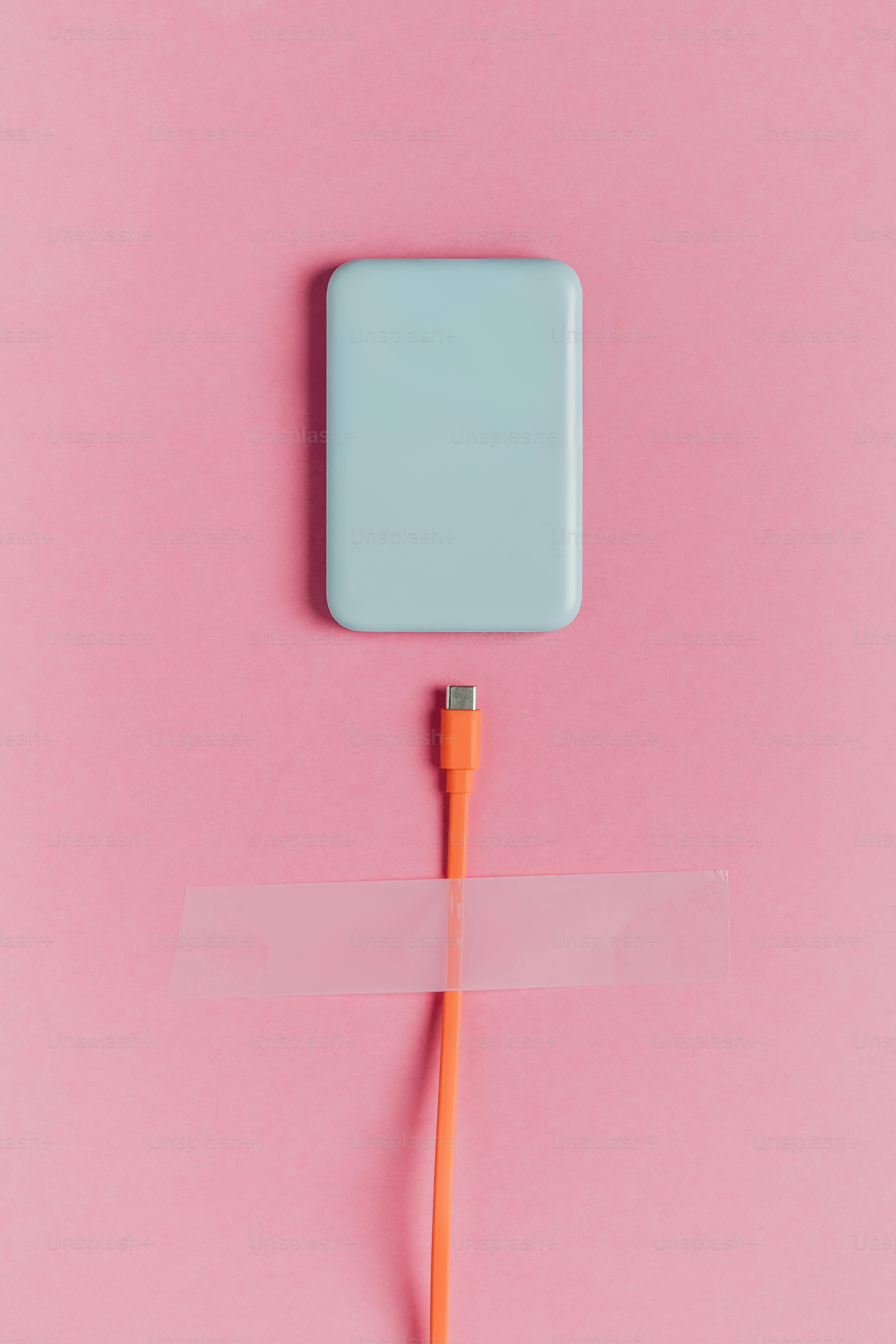 Blue power bank with orange charging cable taped