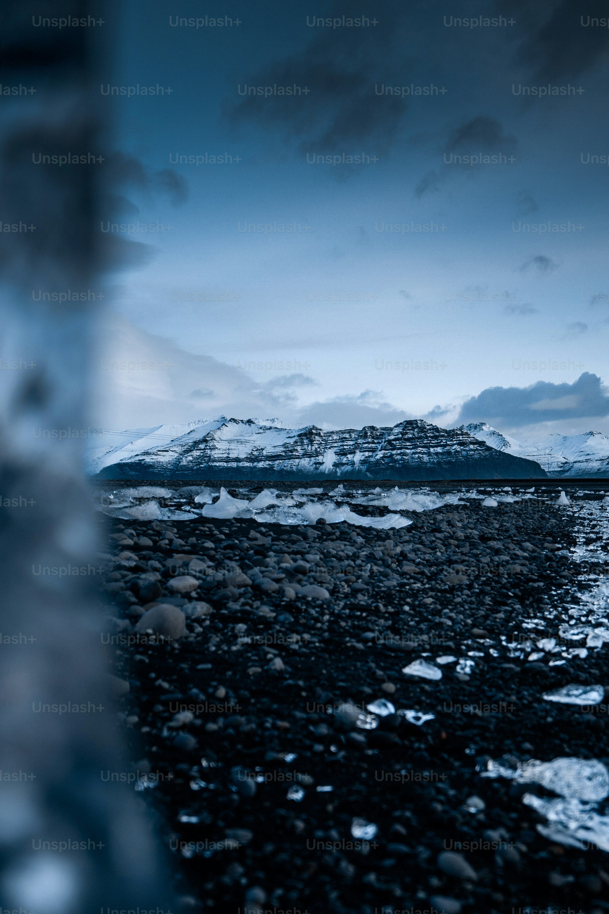 Snow-capped mountains over a rocky, icy landscape