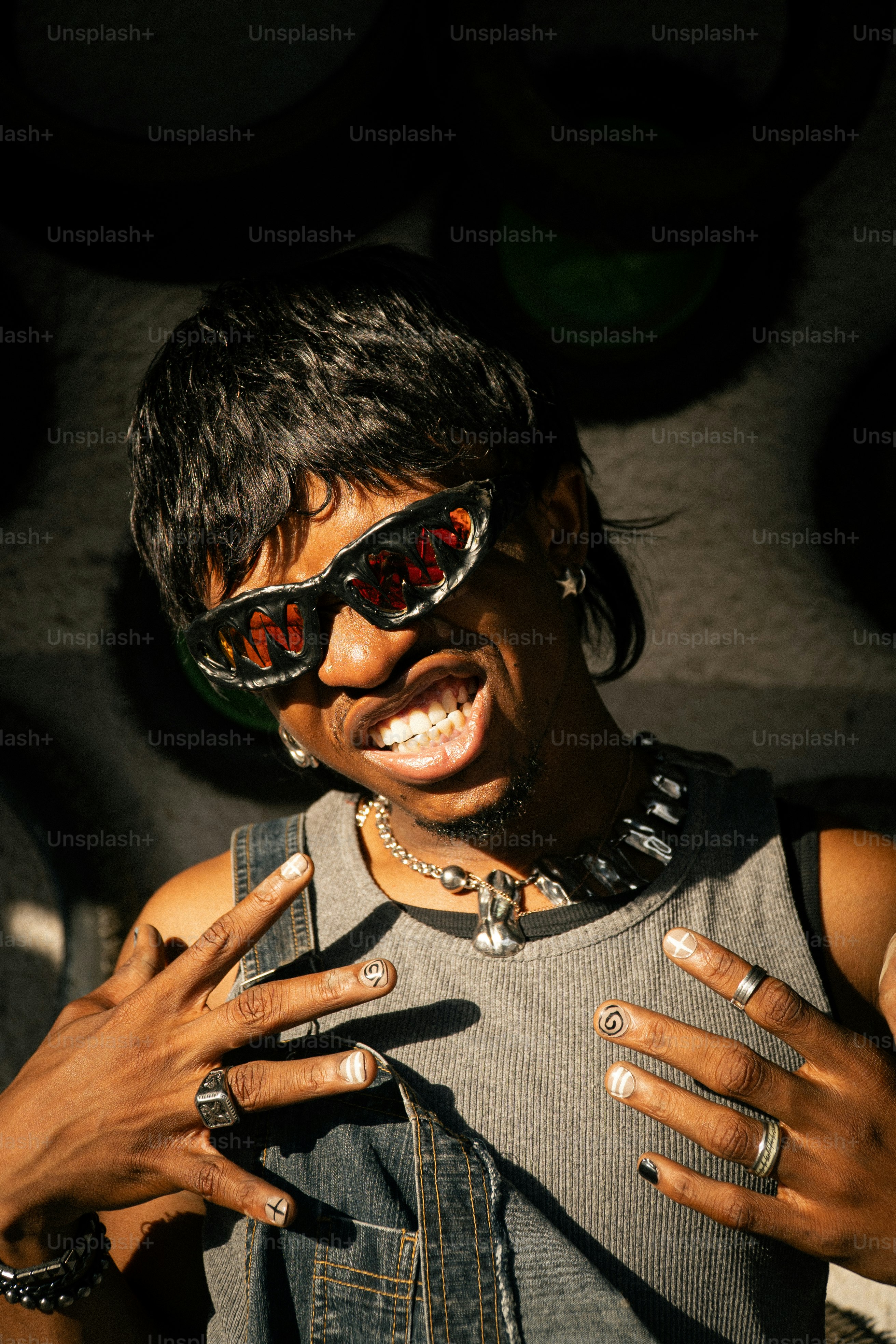 Hombre con gafas de sol y joyas luciendo uñas