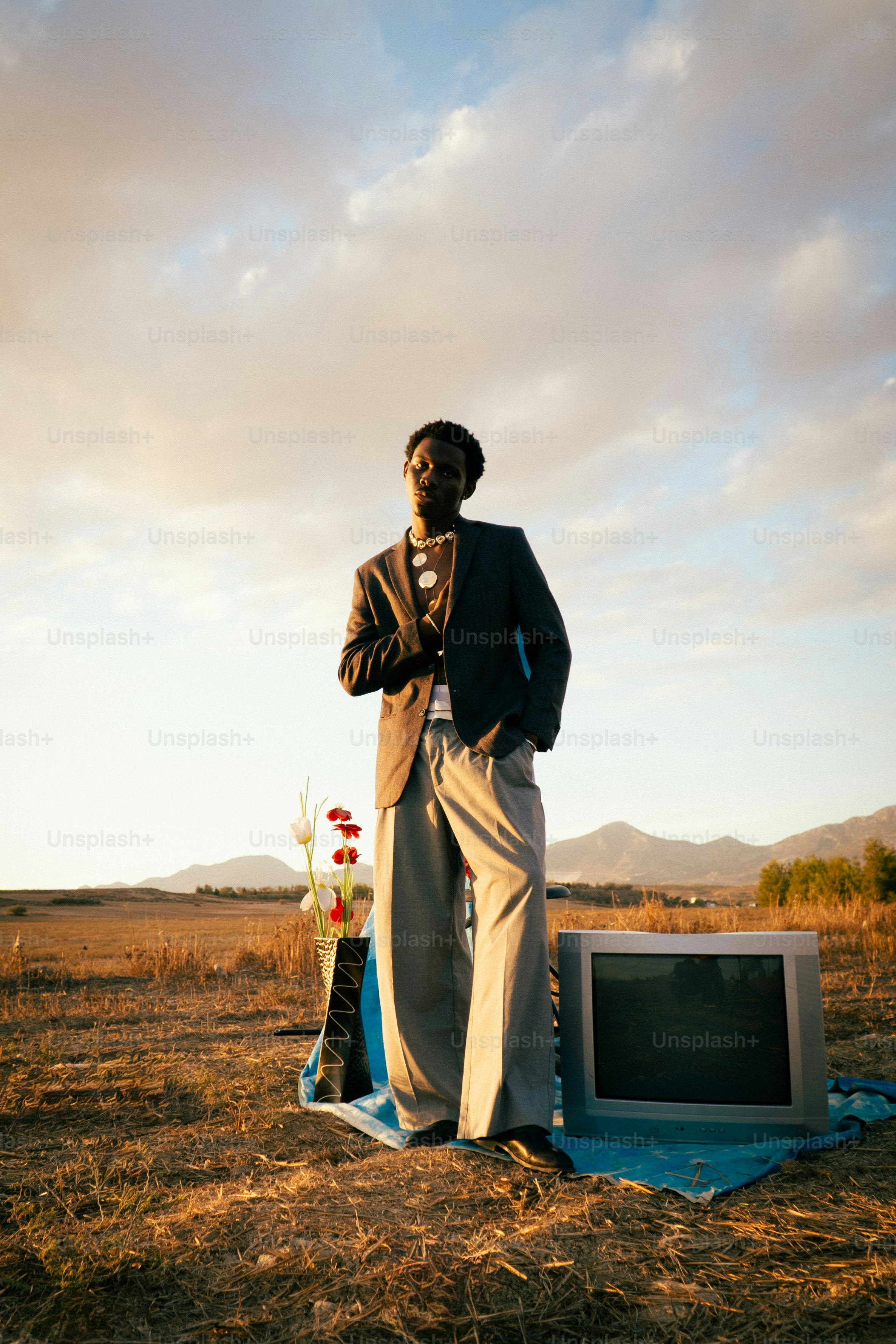 Hombre de traje se para cerca de un televisor antiguo en el campo.