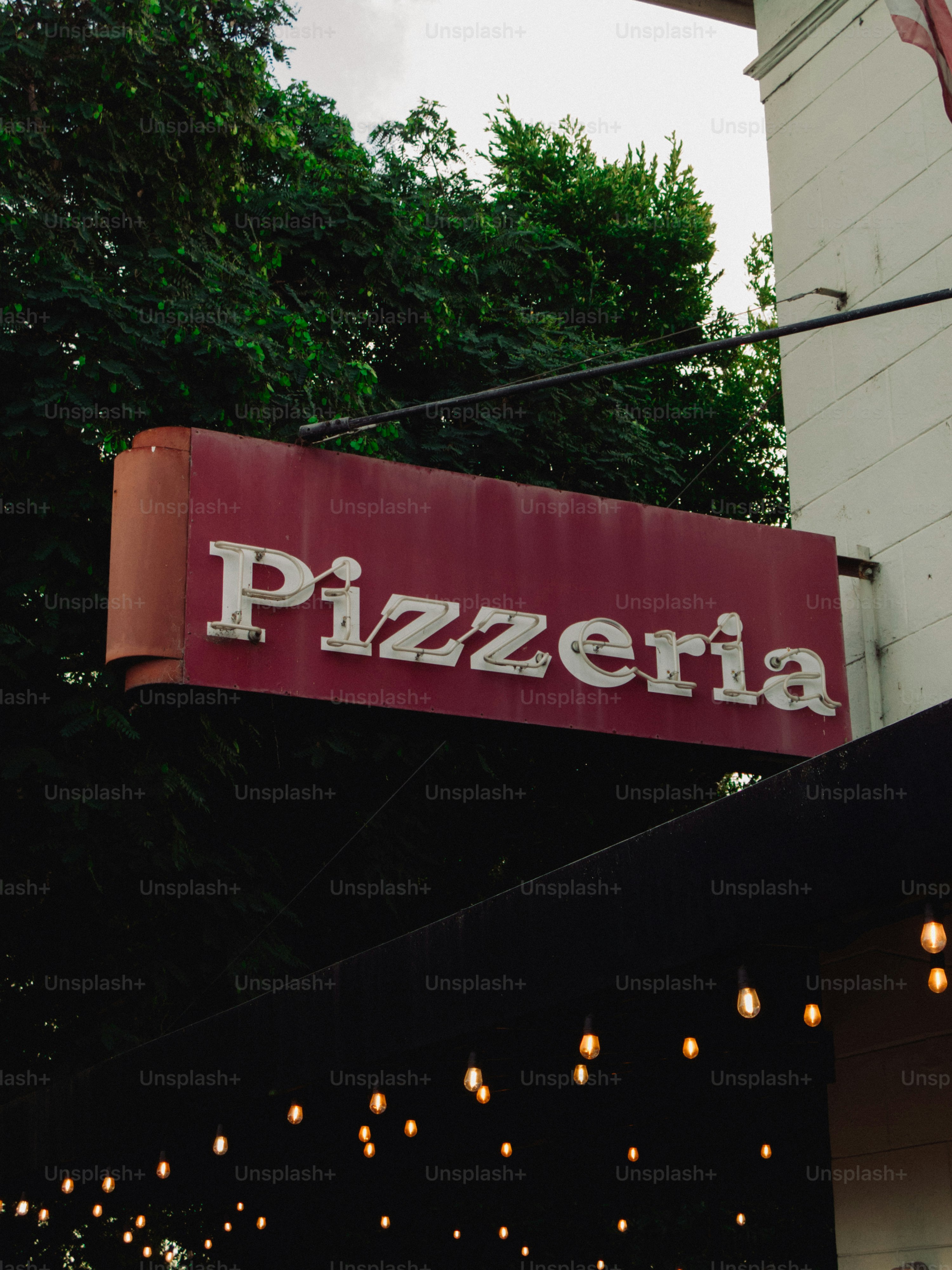 A red sign reads pizzeria above string lights