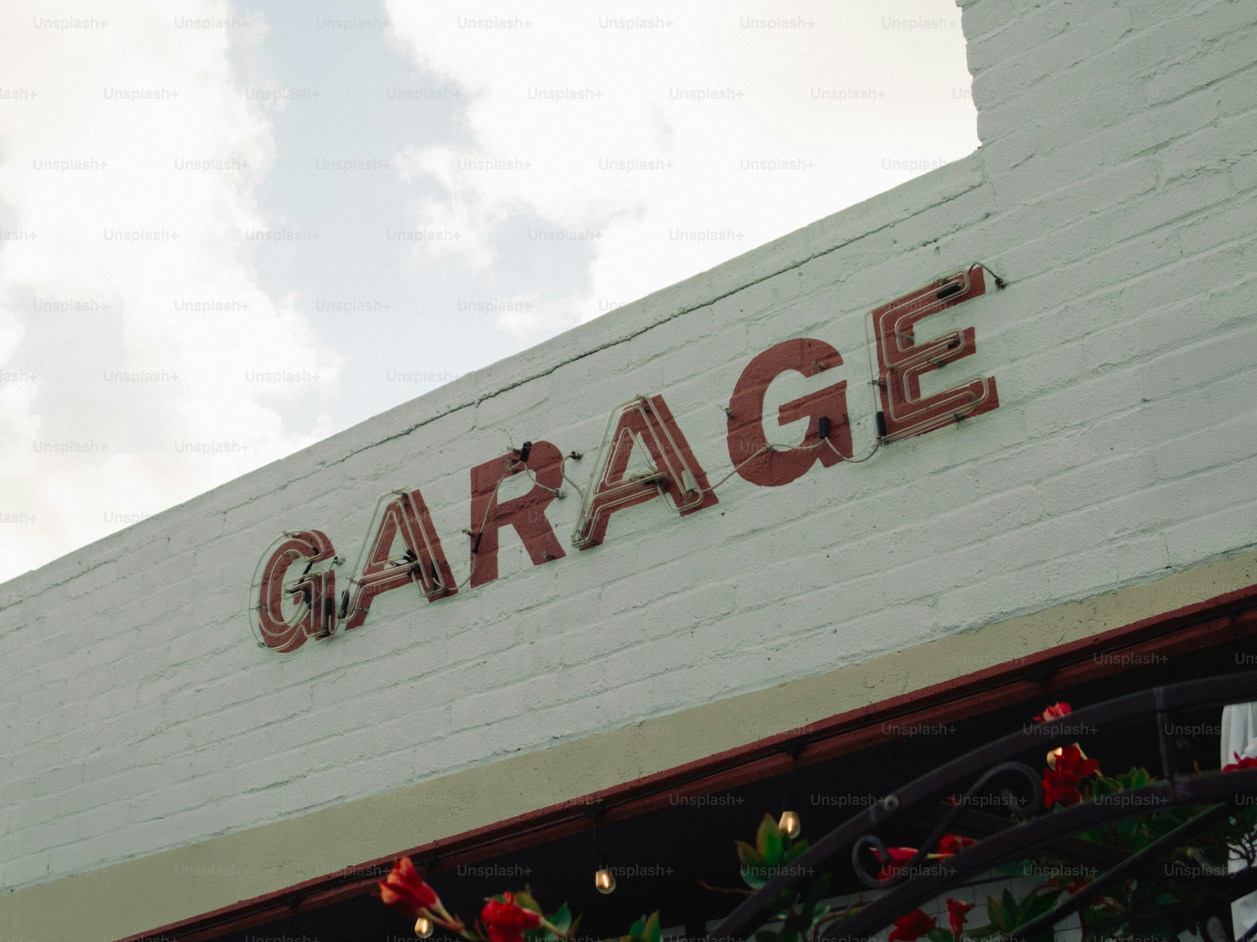 A neon garage sign on a white brick building