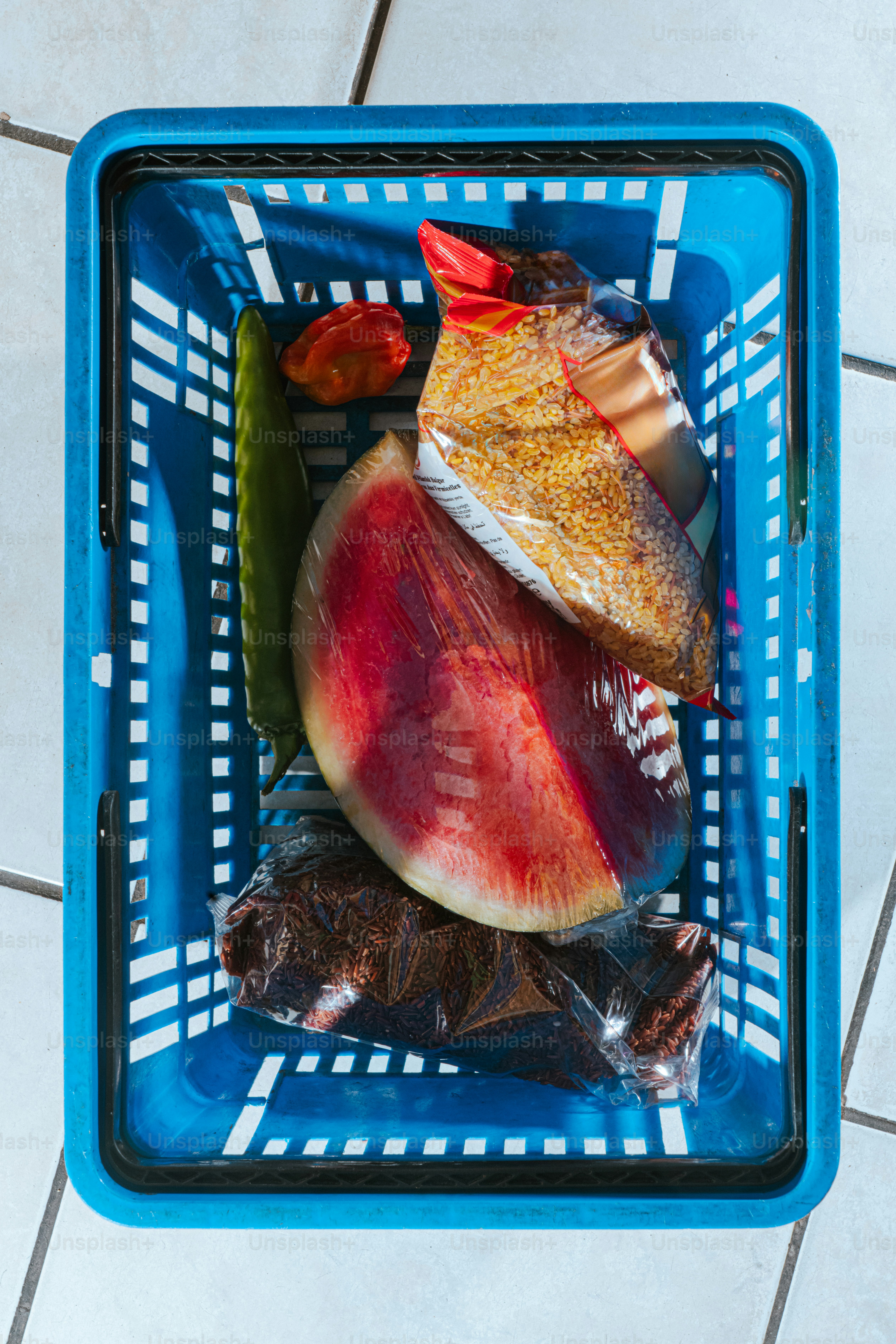 Cesta azul llena de comestibles y productos.