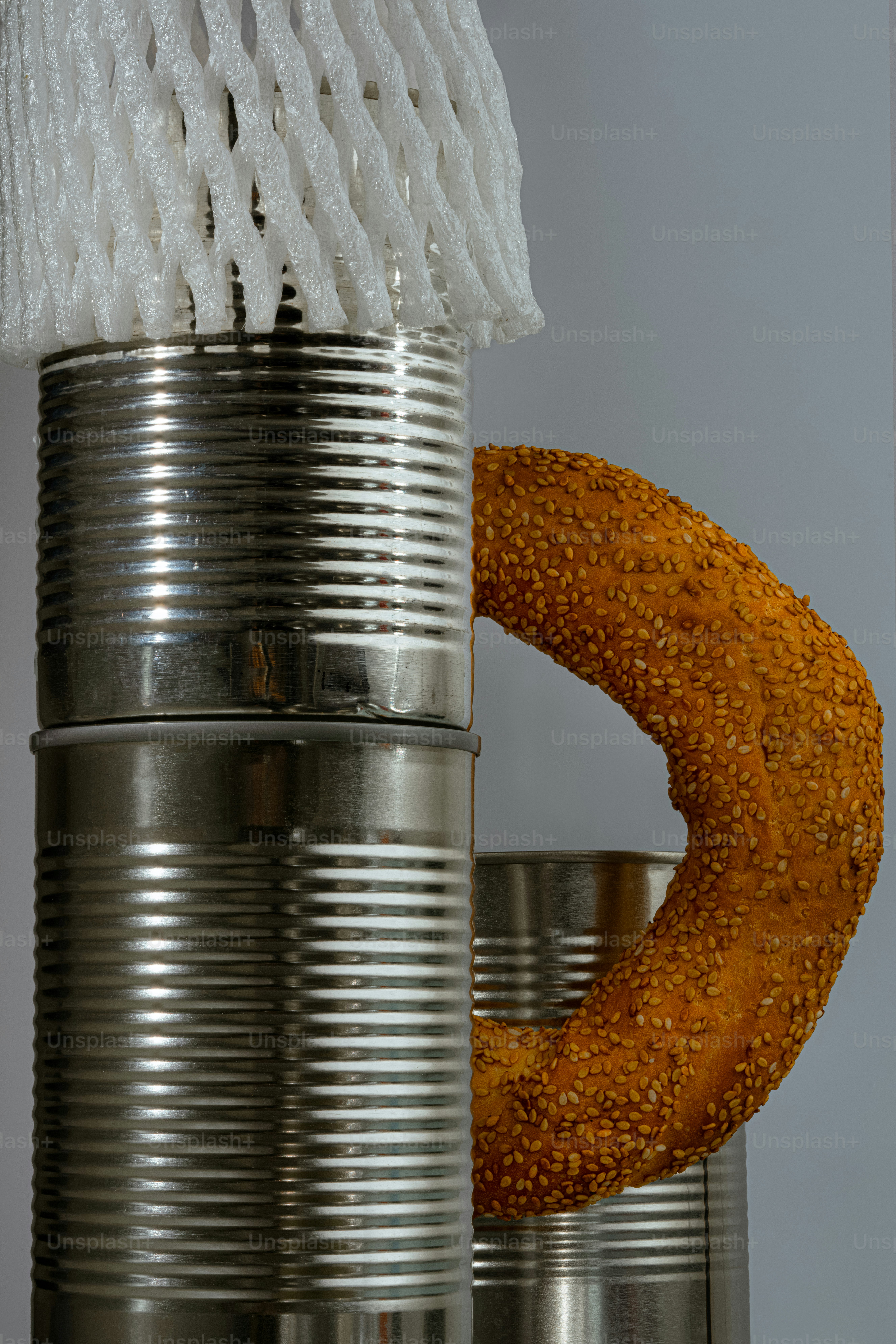 Stack of tin cans with a sesame seed bagel.