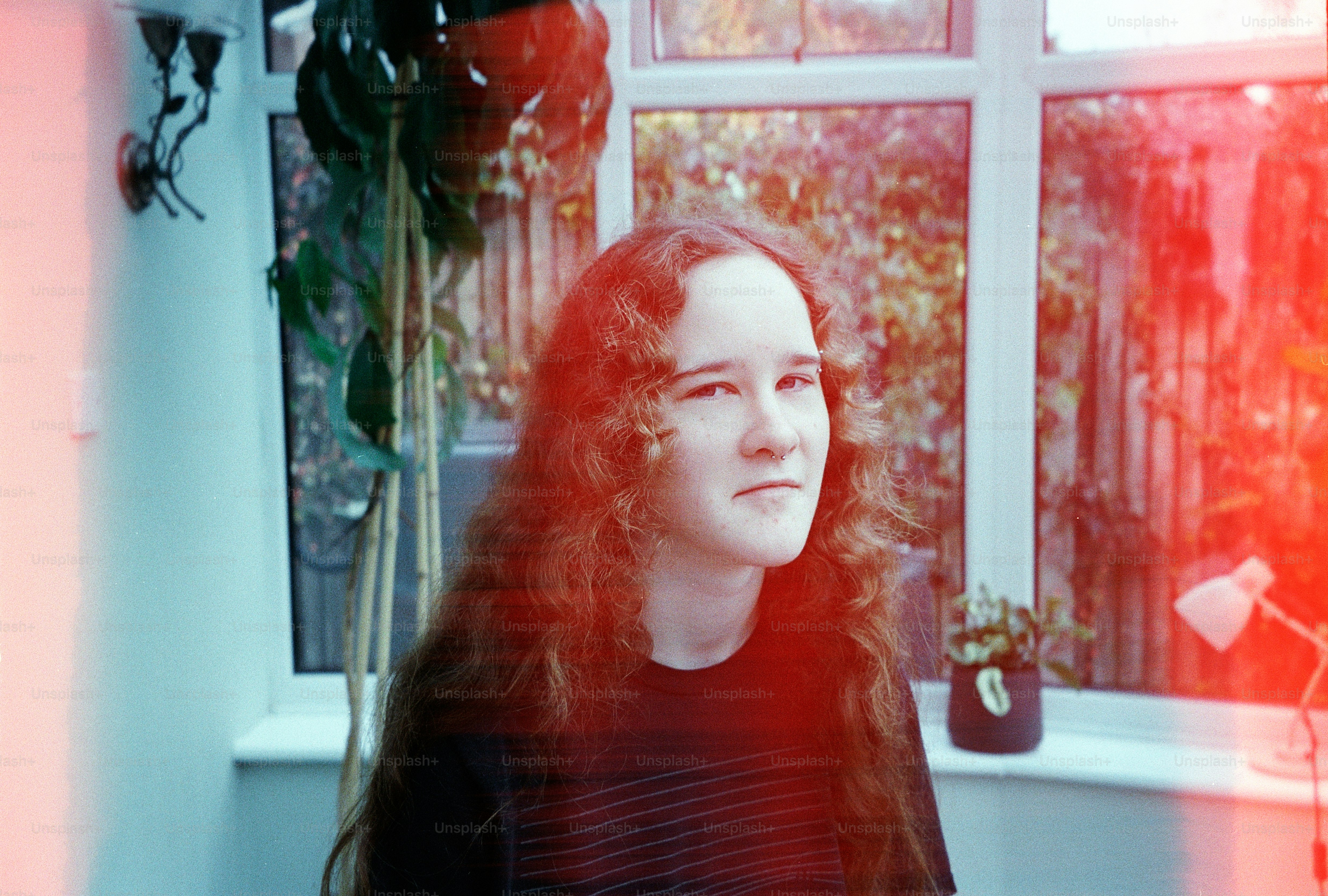 Young woman with long curly hair in a sunroom.